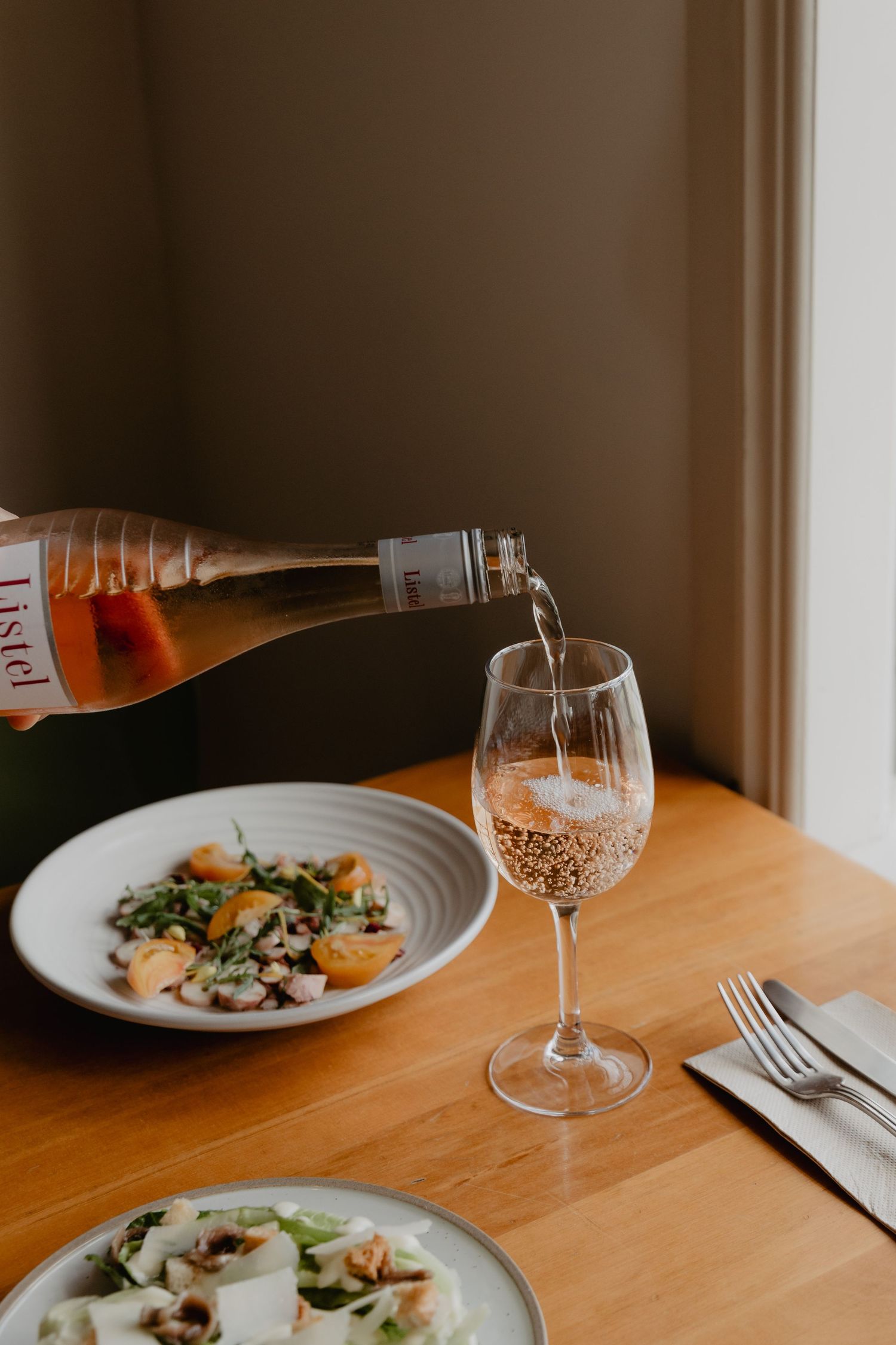 Elegant table setting with wine glasses and plated dishes on wooden surface.