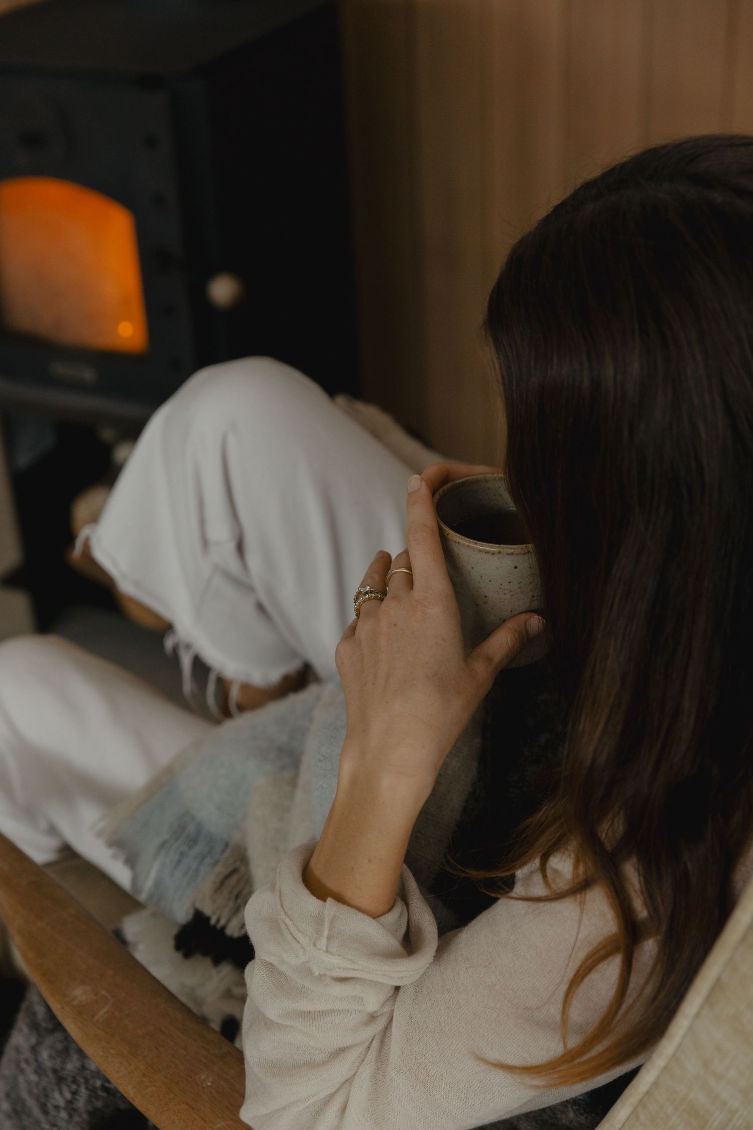 Person enjoying a warm beverage while relaxing on a couch.
