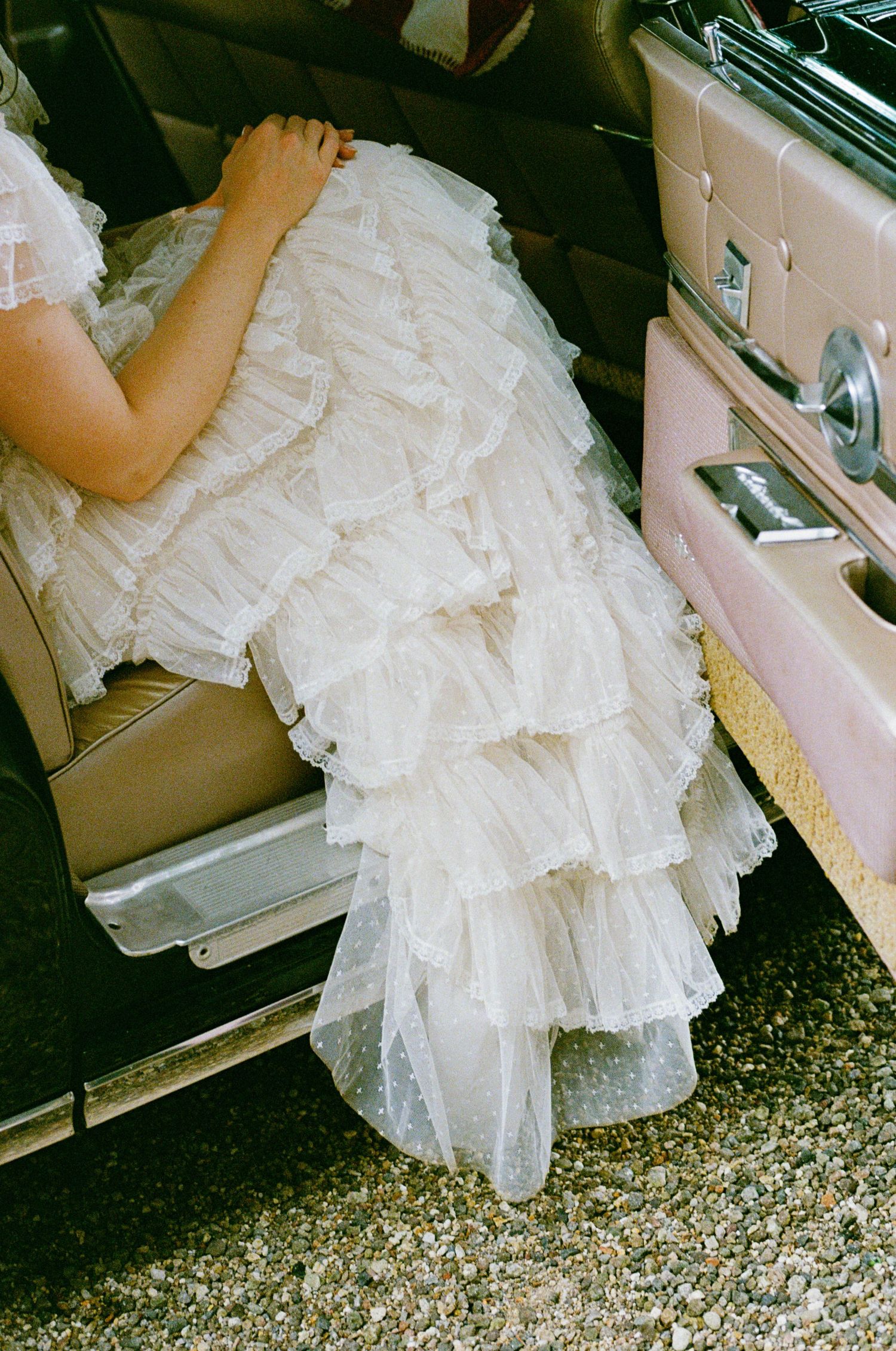 White ruffled tulle dress detail shown through car window.