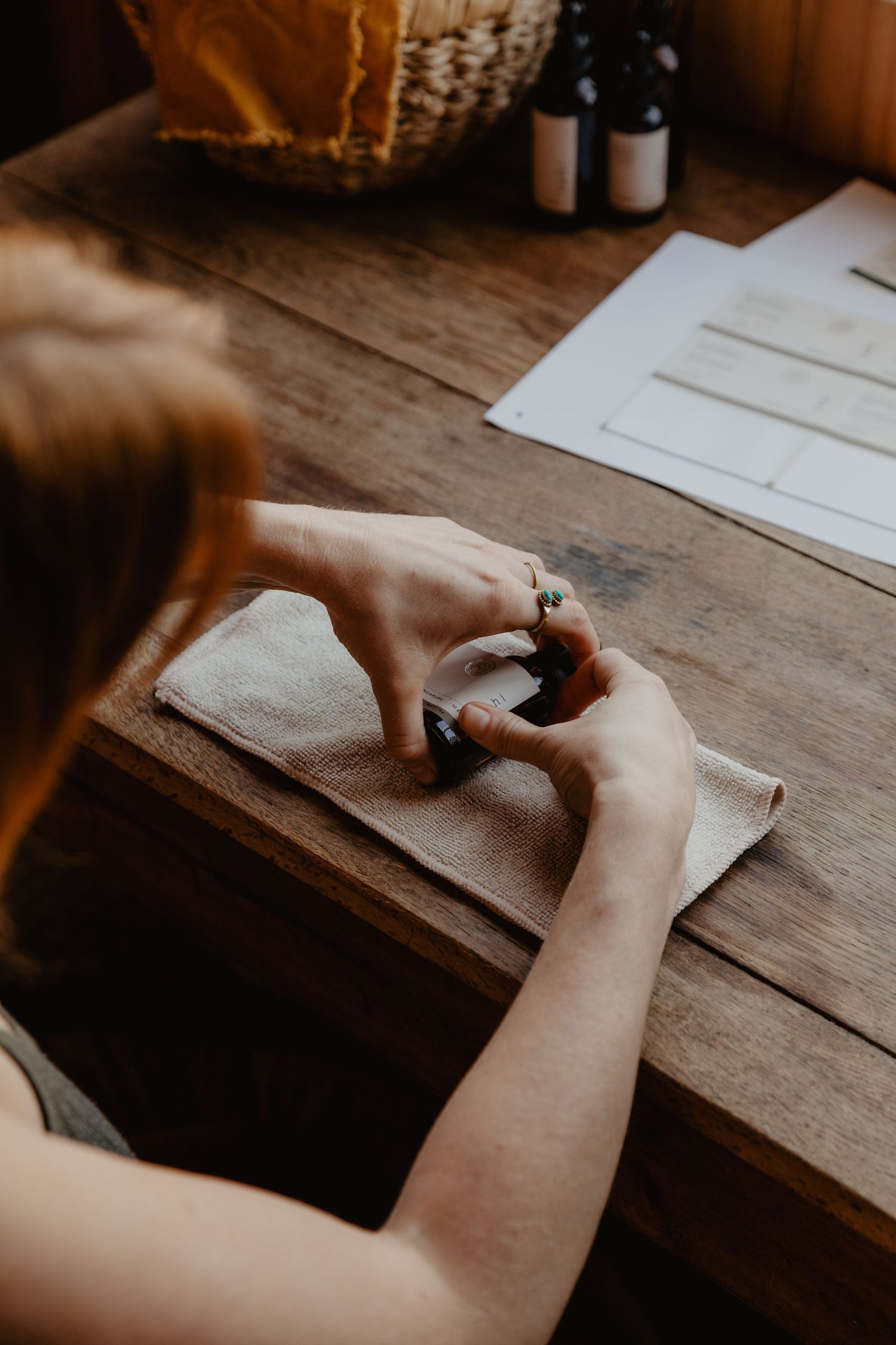 Hands writing or drawing on paper at a rustic wooden table.