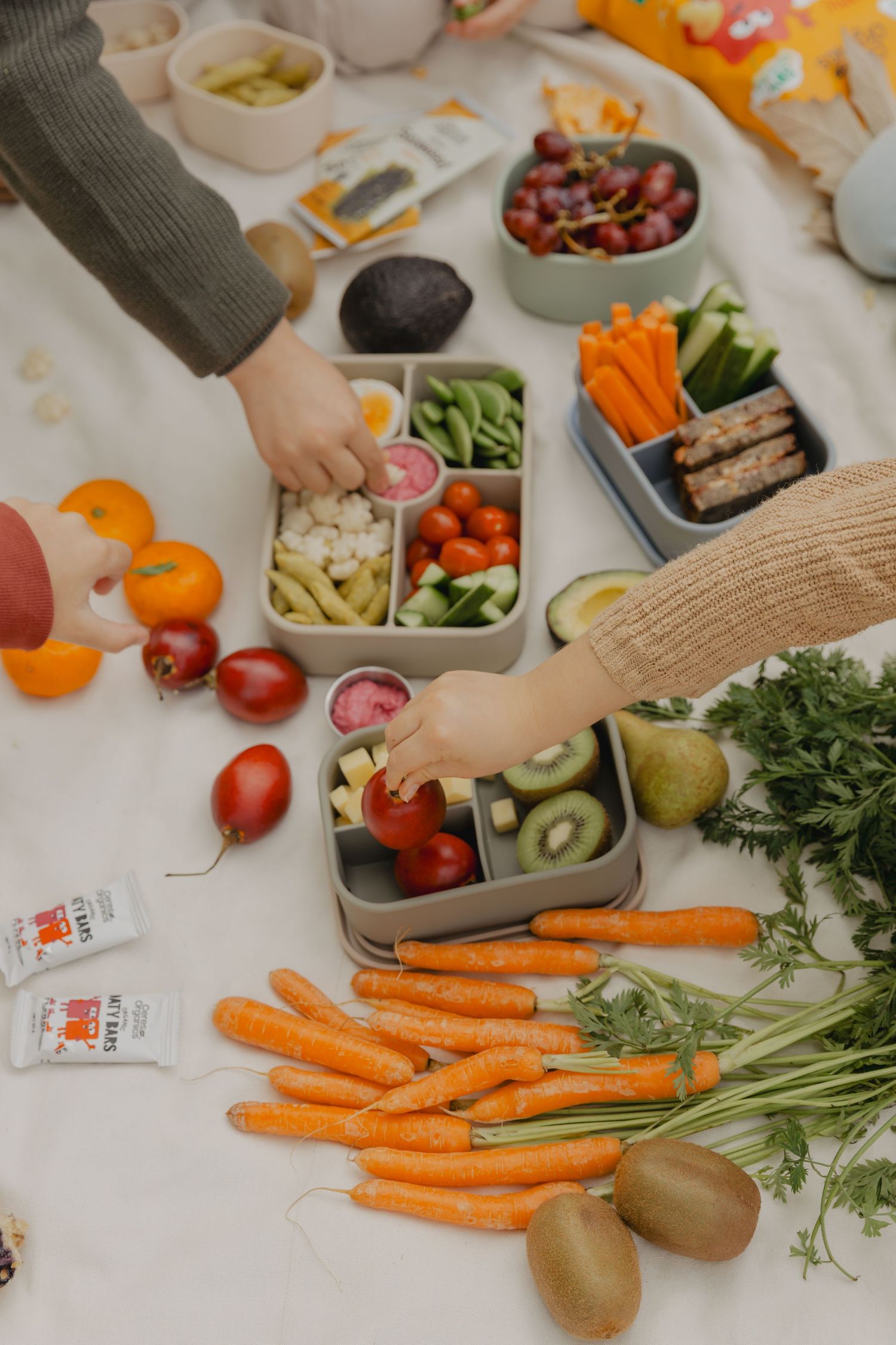 Fresh vegetables and produce arranged on a white surface with compartmented containers.