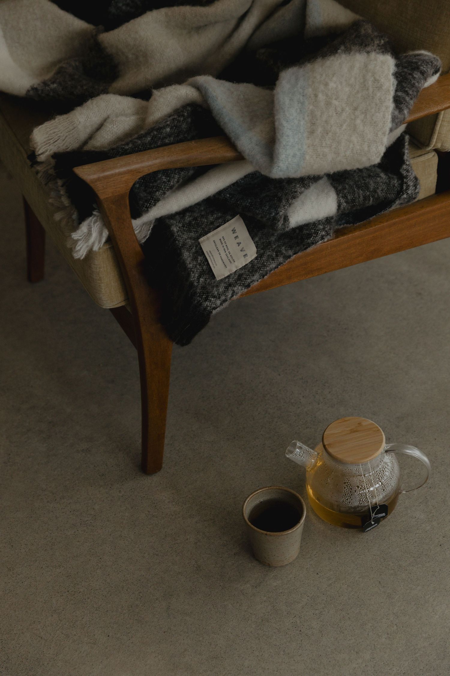 Cozy tea setting with blankets and ceramic cups on wooden bench.