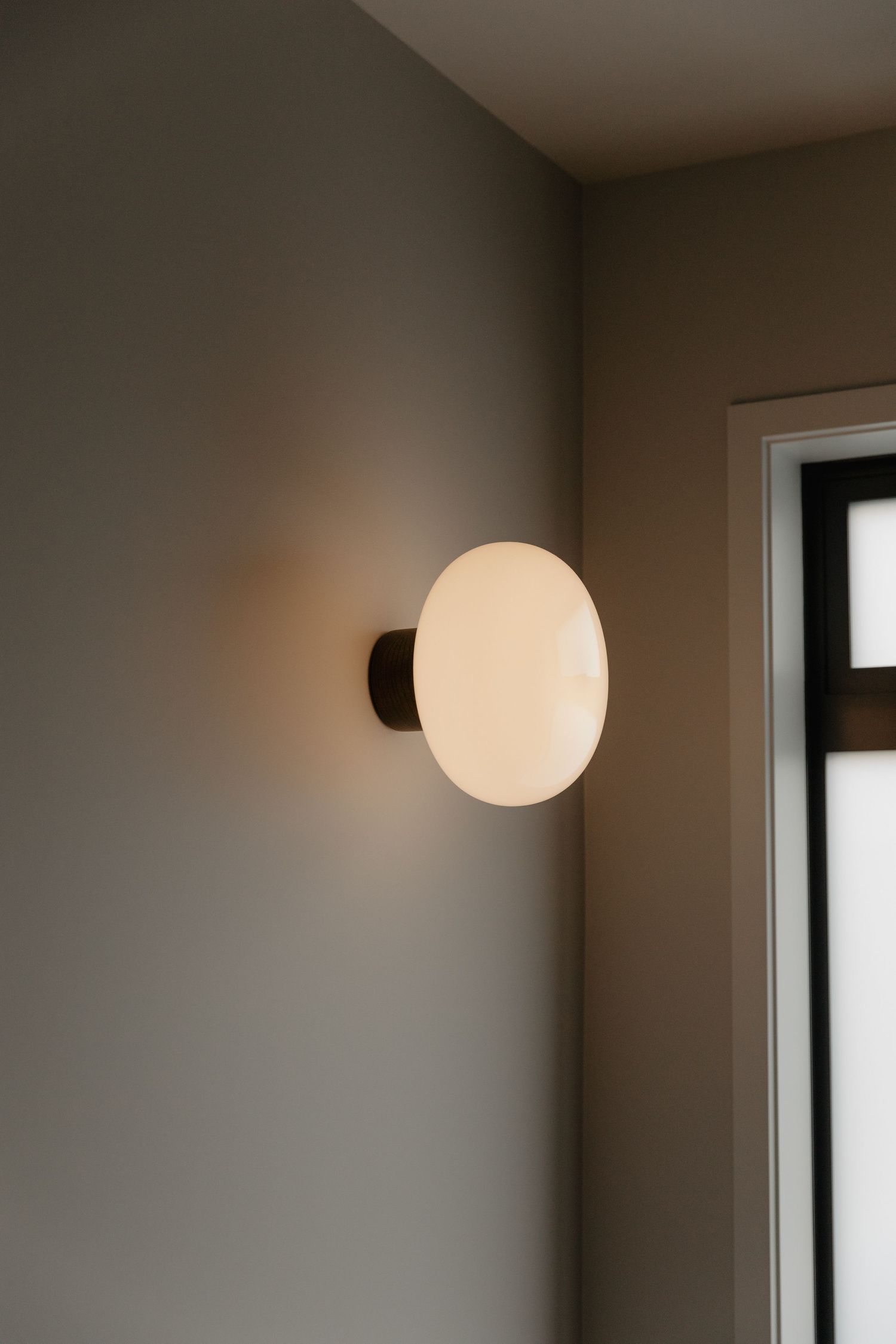 Minimalist wall design with round white sconce lighting fixture.
