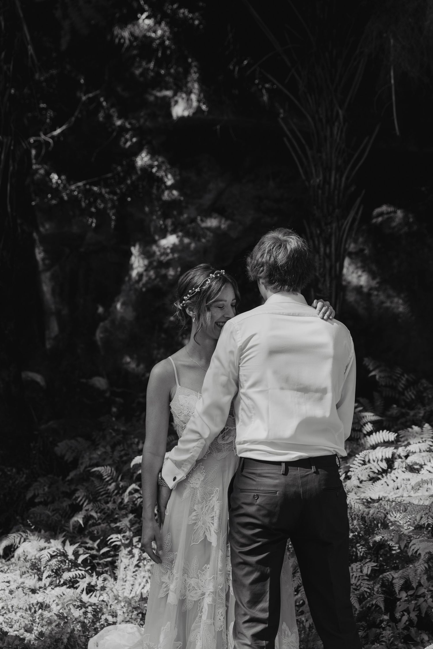 A romantic black and white photo of a couple embracing in a garden setting.