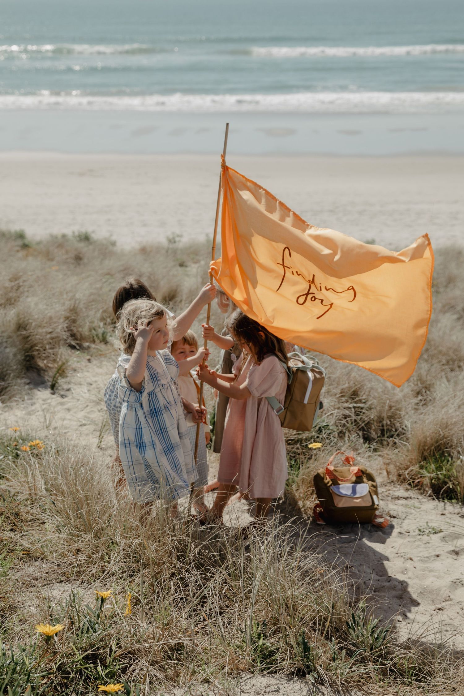 An orange flag waves on the beach as people gather for a seaside picnic.