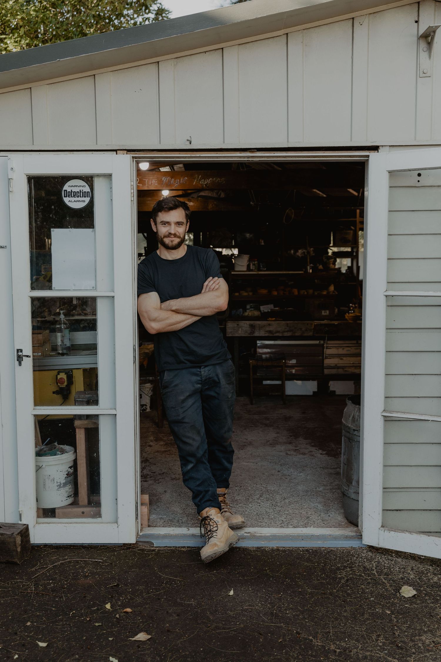 Workshop entrance with tools visible inside white wooden garage.