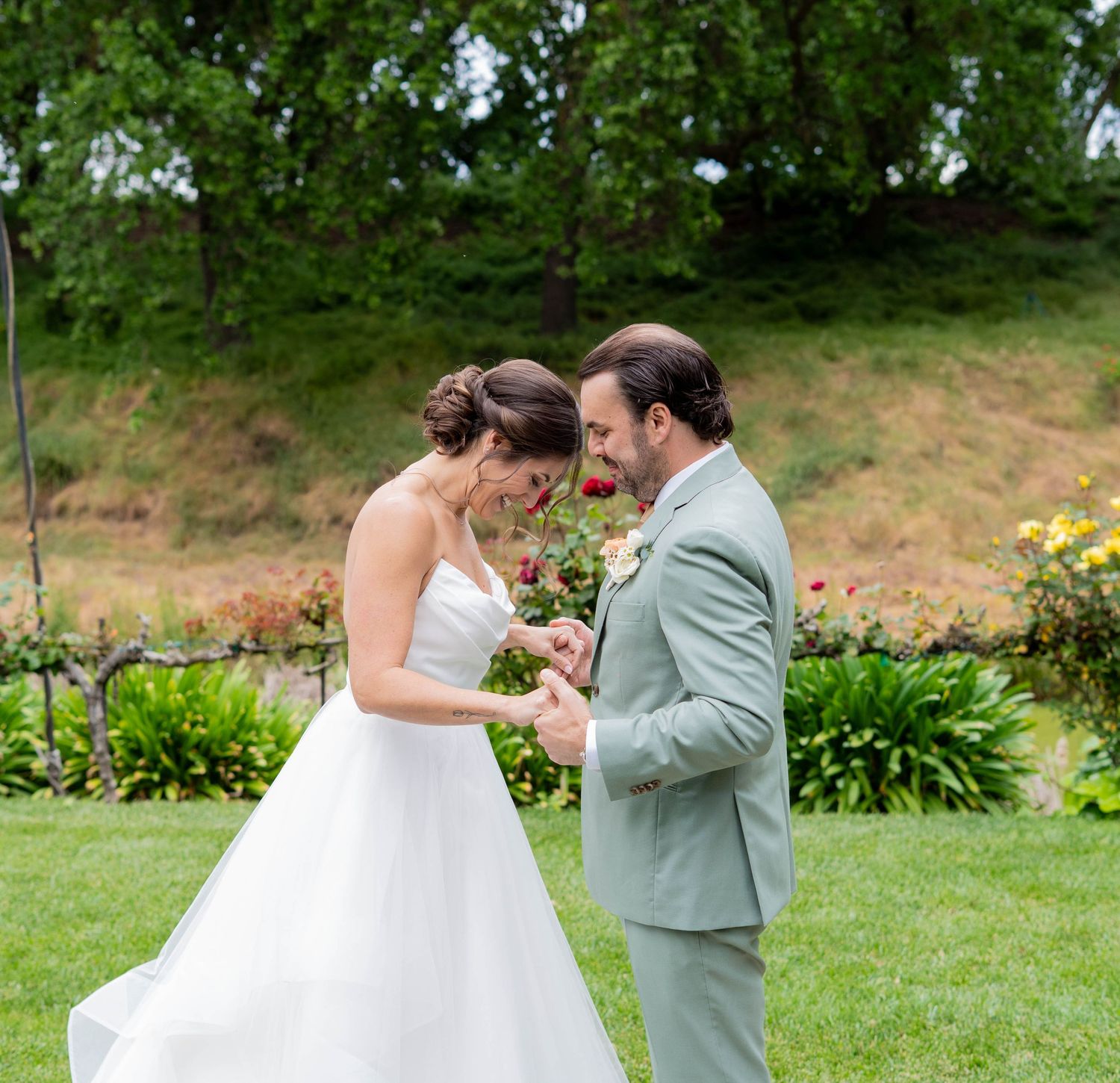 Couple sharing a romantic moment during their first look in a lush garden setting.