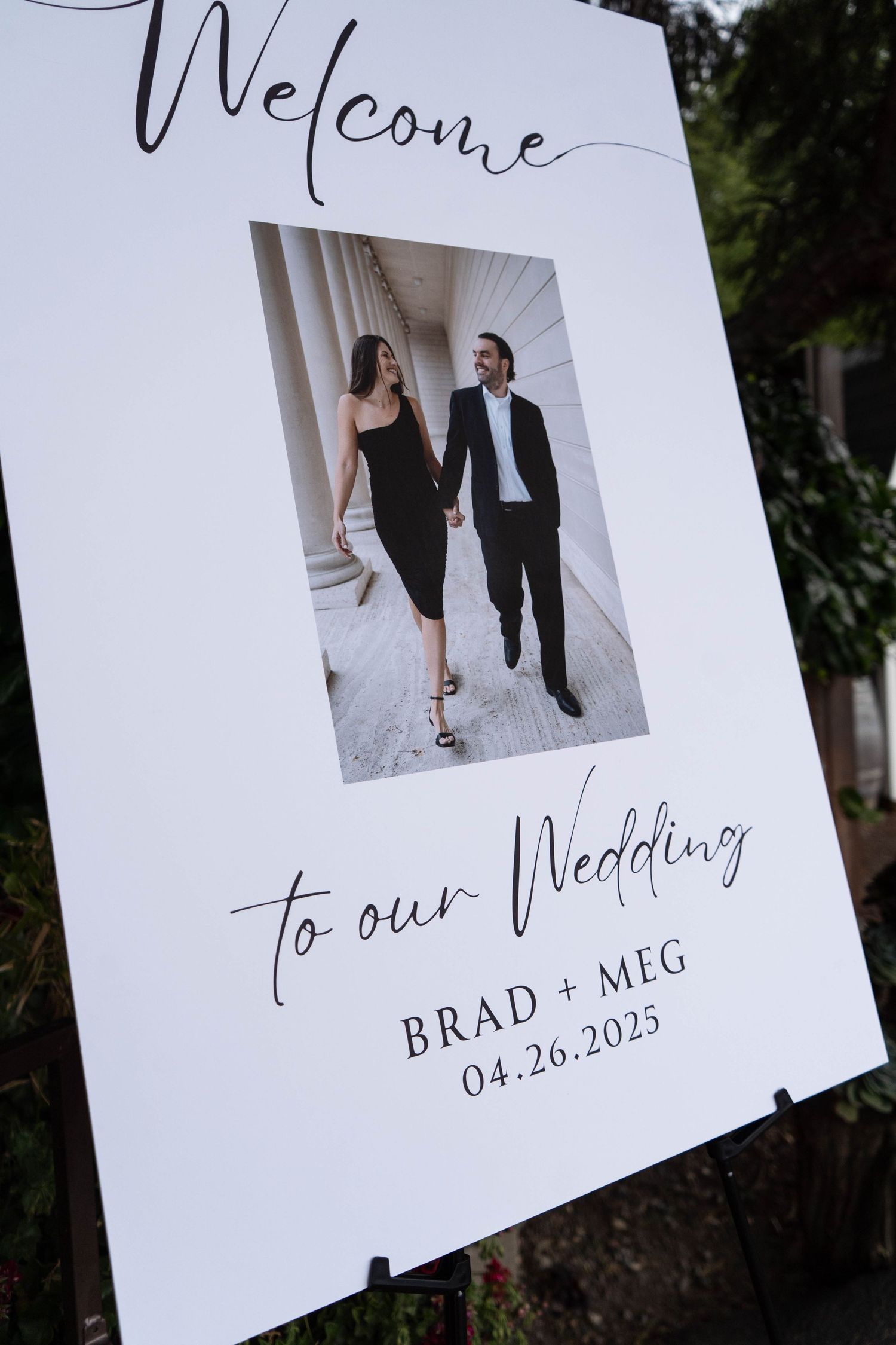 Wedding welcome sign displays elegant calligraphy and couple's photos with date April 26, 2025.