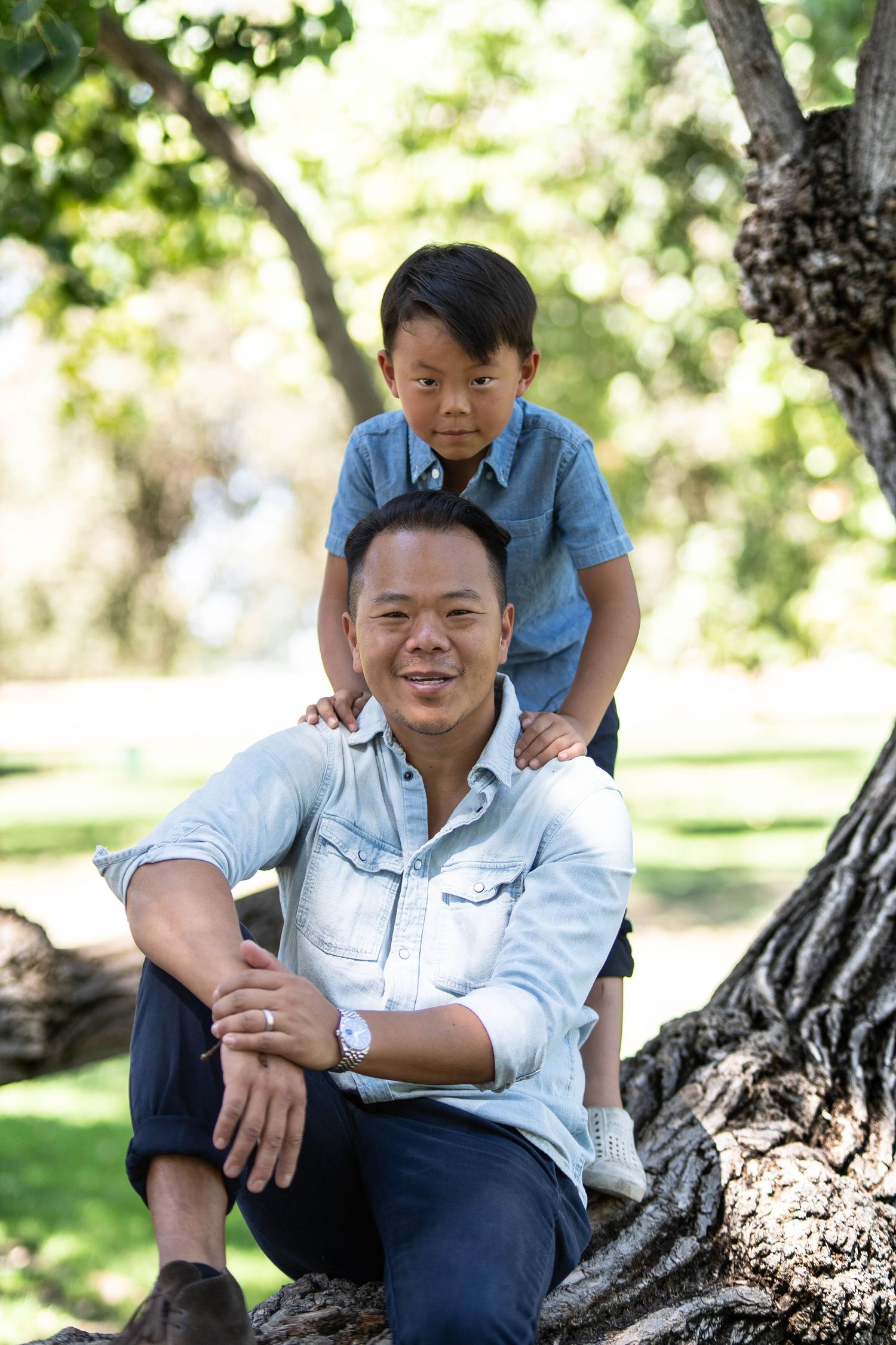 Candid family photos taken under shady tree in park setting.
