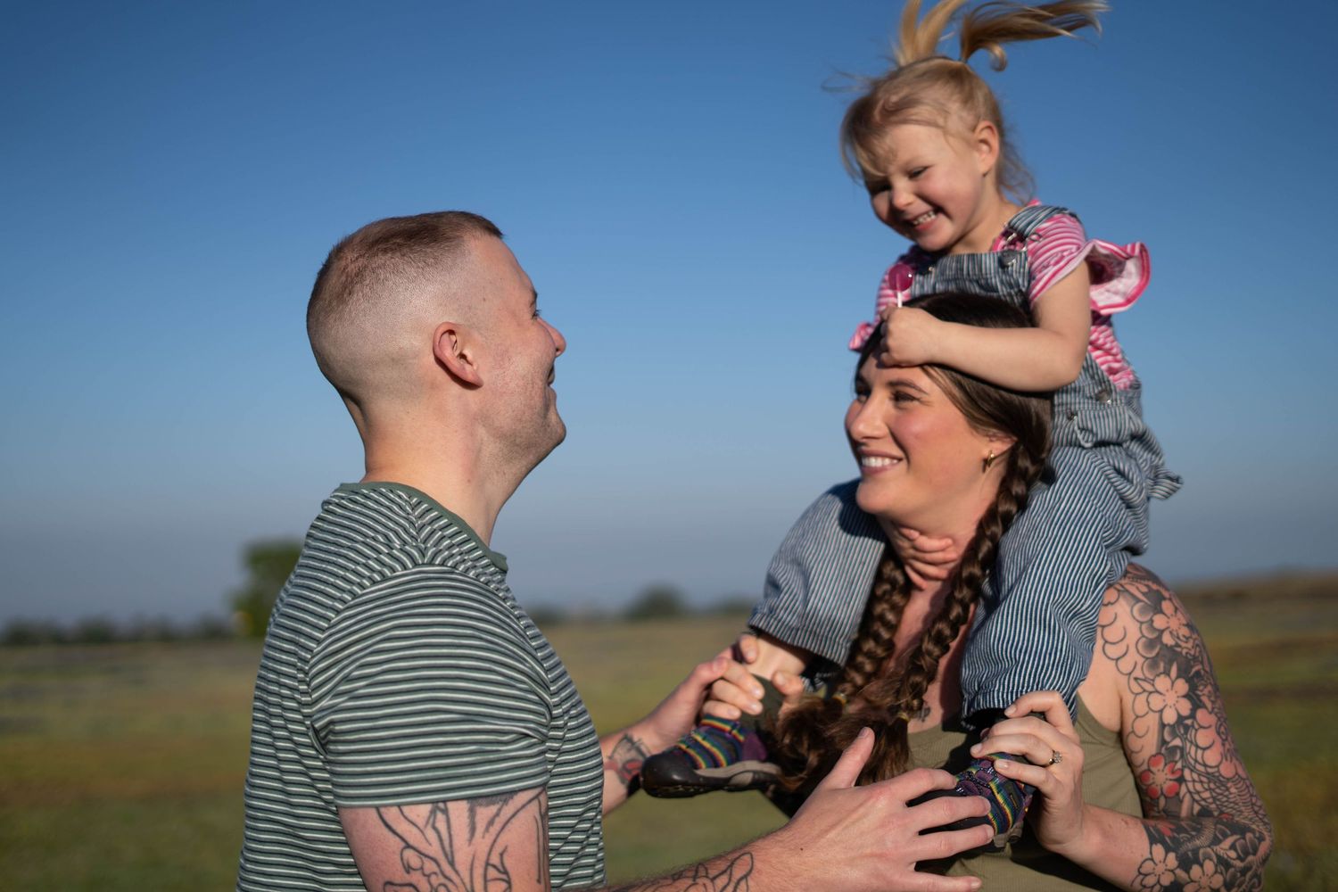 Outdoor family photography session with candid moments against blue sky backdrop.