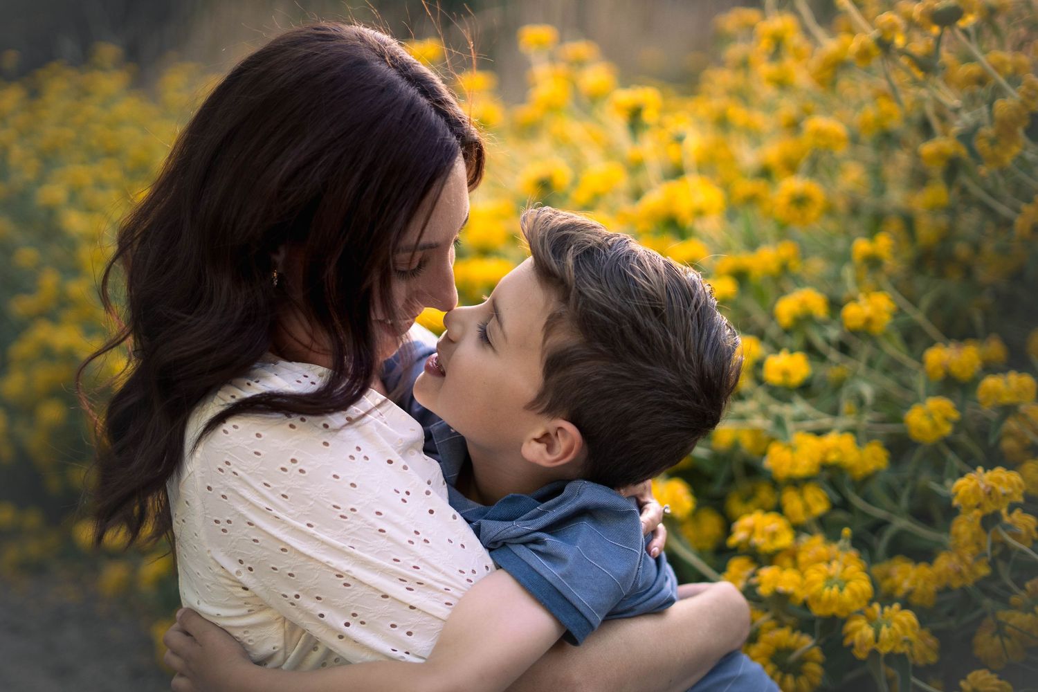 A couple embraces among blooming yellow wildflowers in a golden field.