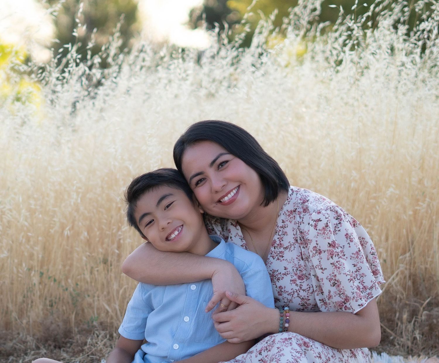 Outdoor family portrait in tall grass with warm sunset lighting.
