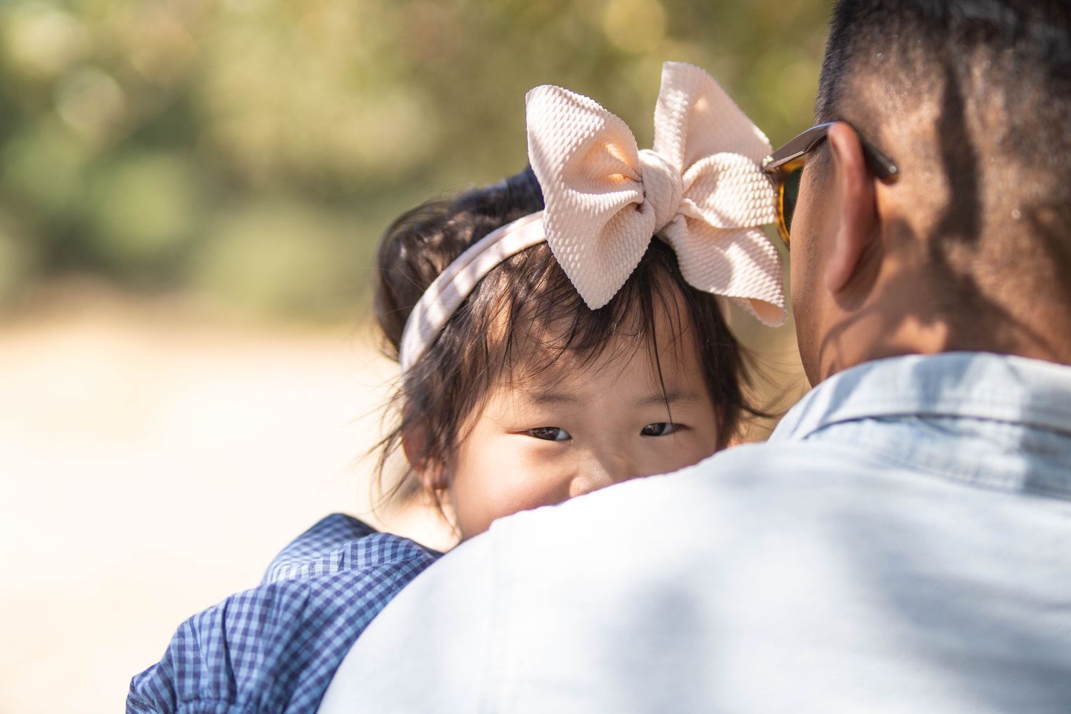 Family moment captured from behind in outdoor sunlit setting.