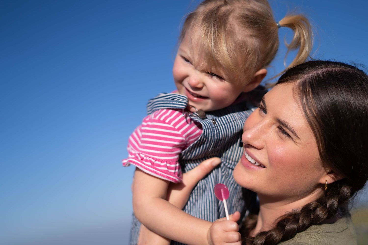 A playful moment between parent and child against a bright blue sky background.