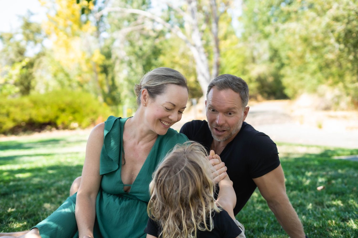 Family portrait session on grassy lawn with joyful candid moments.