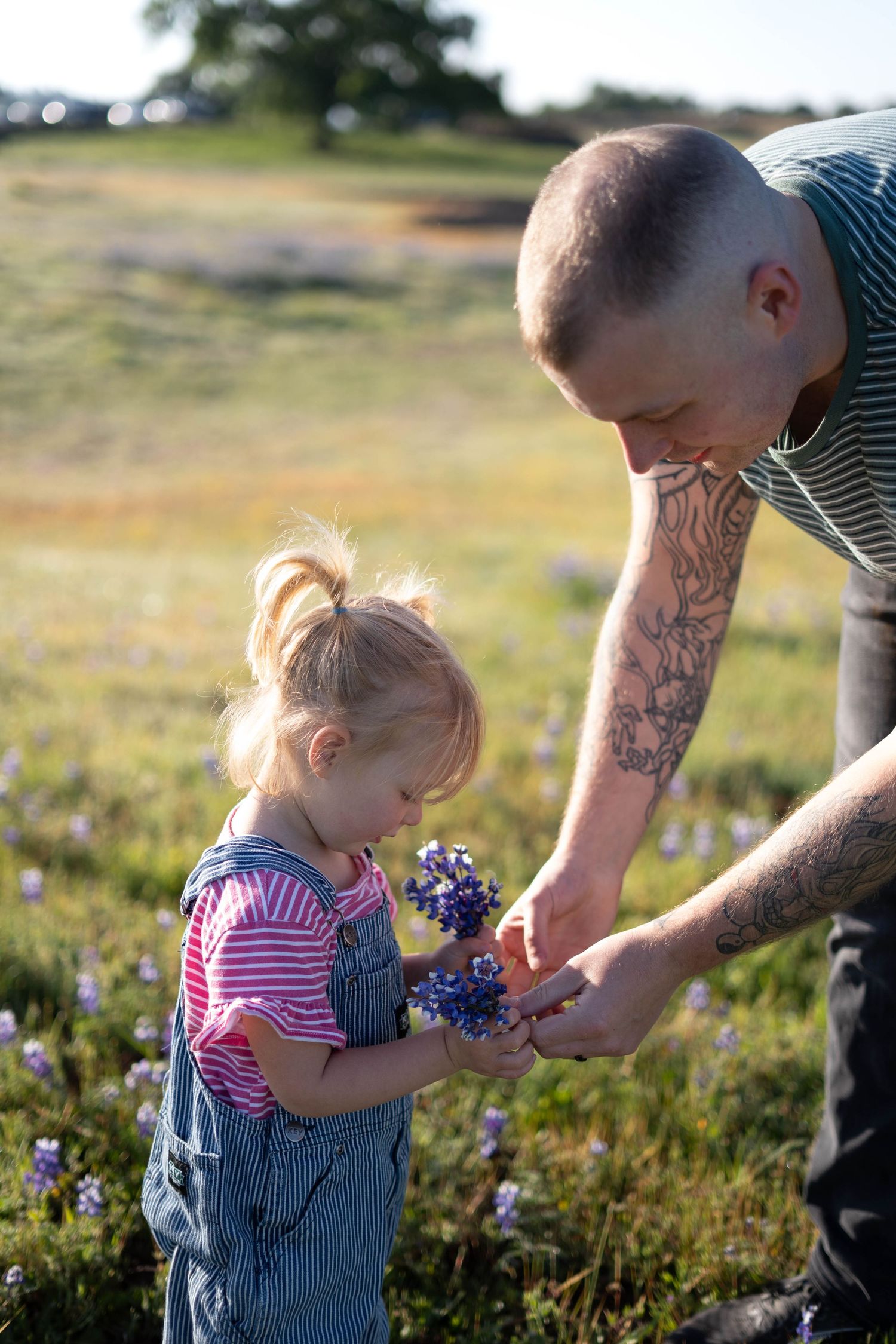 A parent and child share a special moment picking wildflowers together in a sunny meadow.