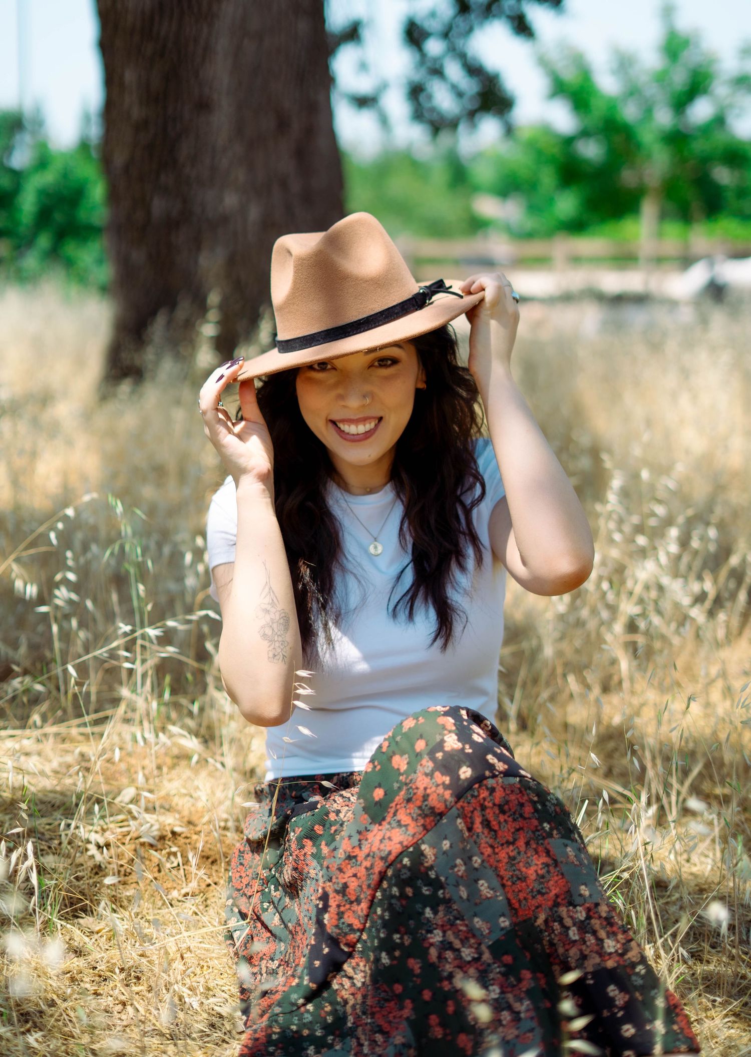 Playful outdoor photography session with sun hat in golden summer field.