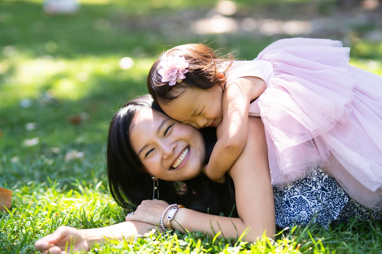 A tender moment between parent and child laying on grass in the sunshine.