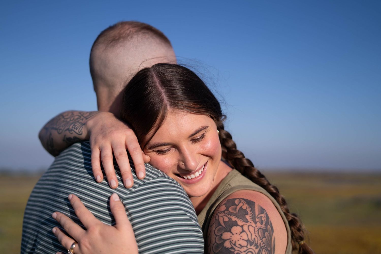 Tender moments between a couple in a vast open field at dusk.