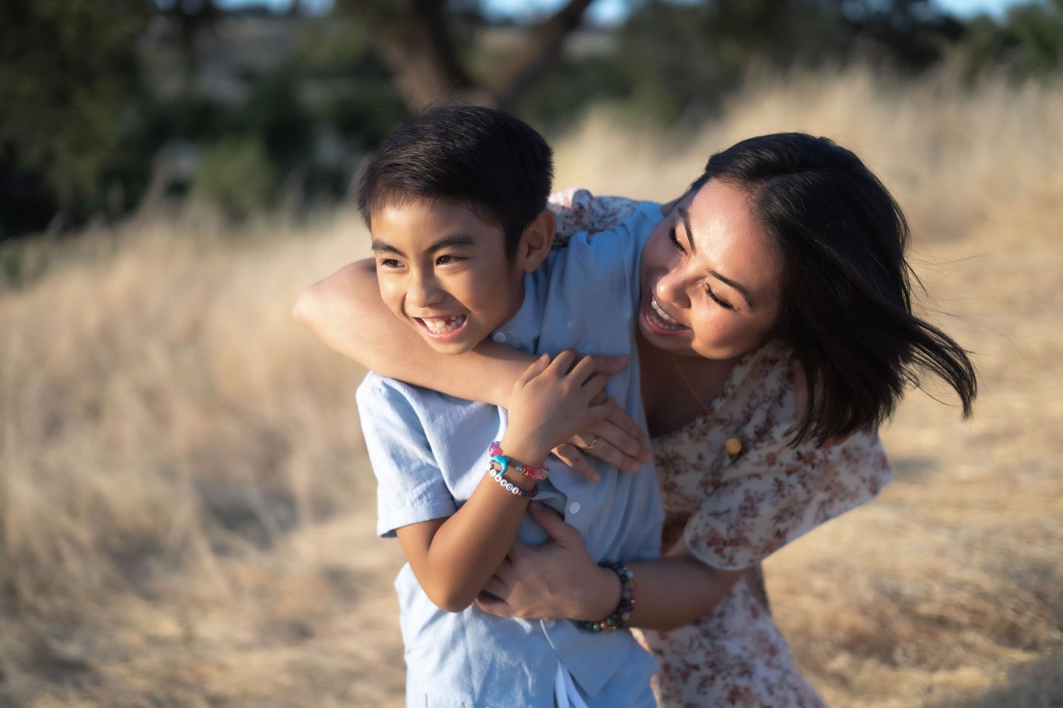 A playful embrace between parent and child in a golden field at sunset.
