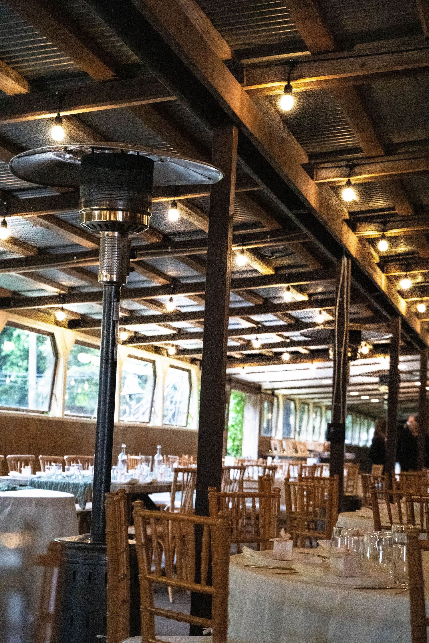 Rustic indoor reception venue with wooden beams and string lights creates warm ambiance.