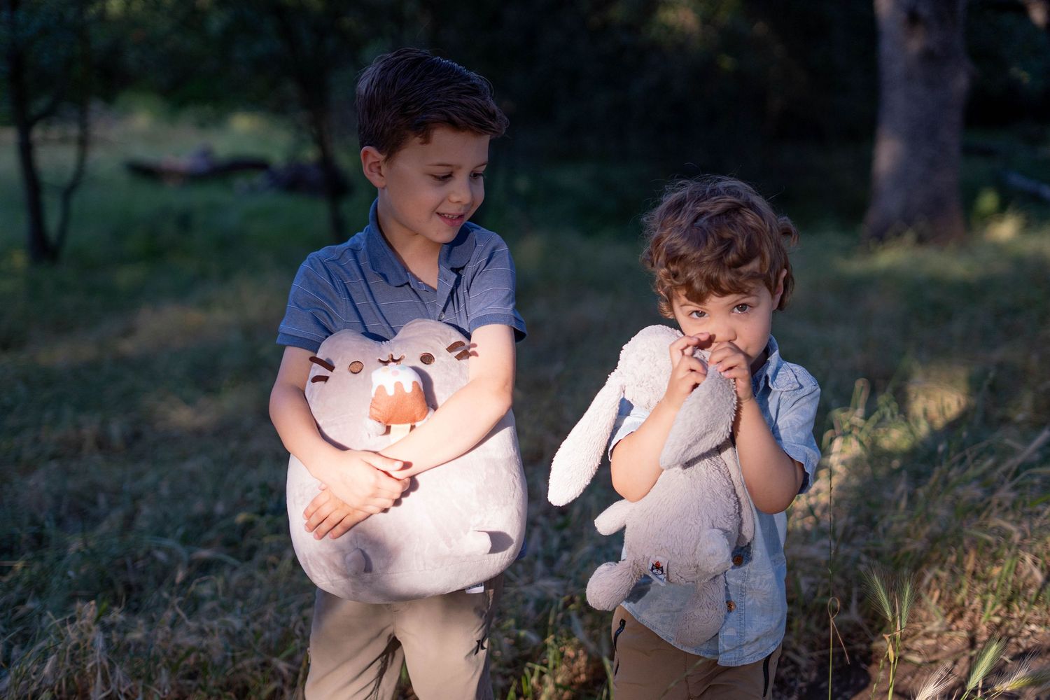 Children playing together on a grassy hillside at sunset.