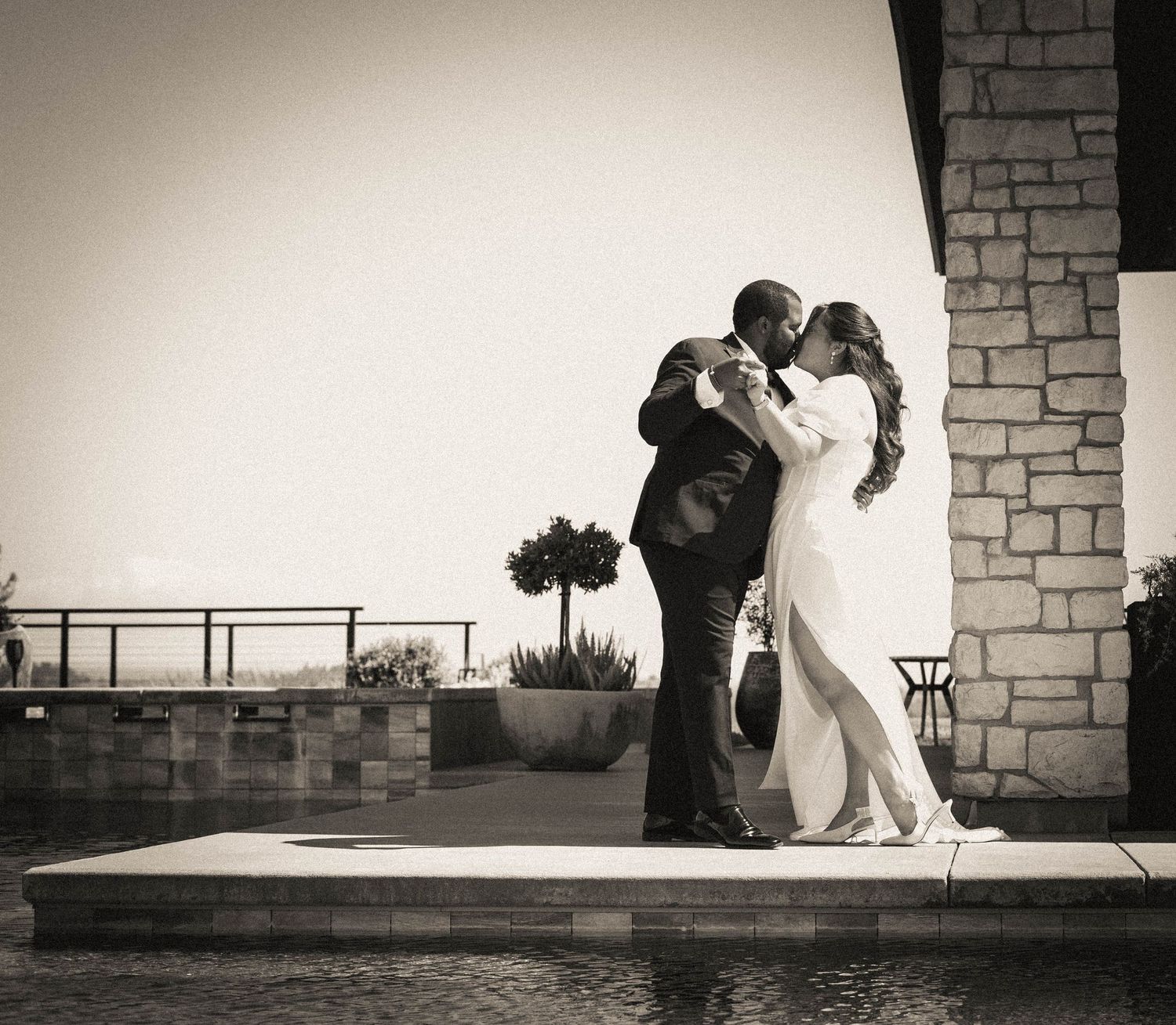 Black and white silhouettes against stone wall during sunset wedding photoshoot.