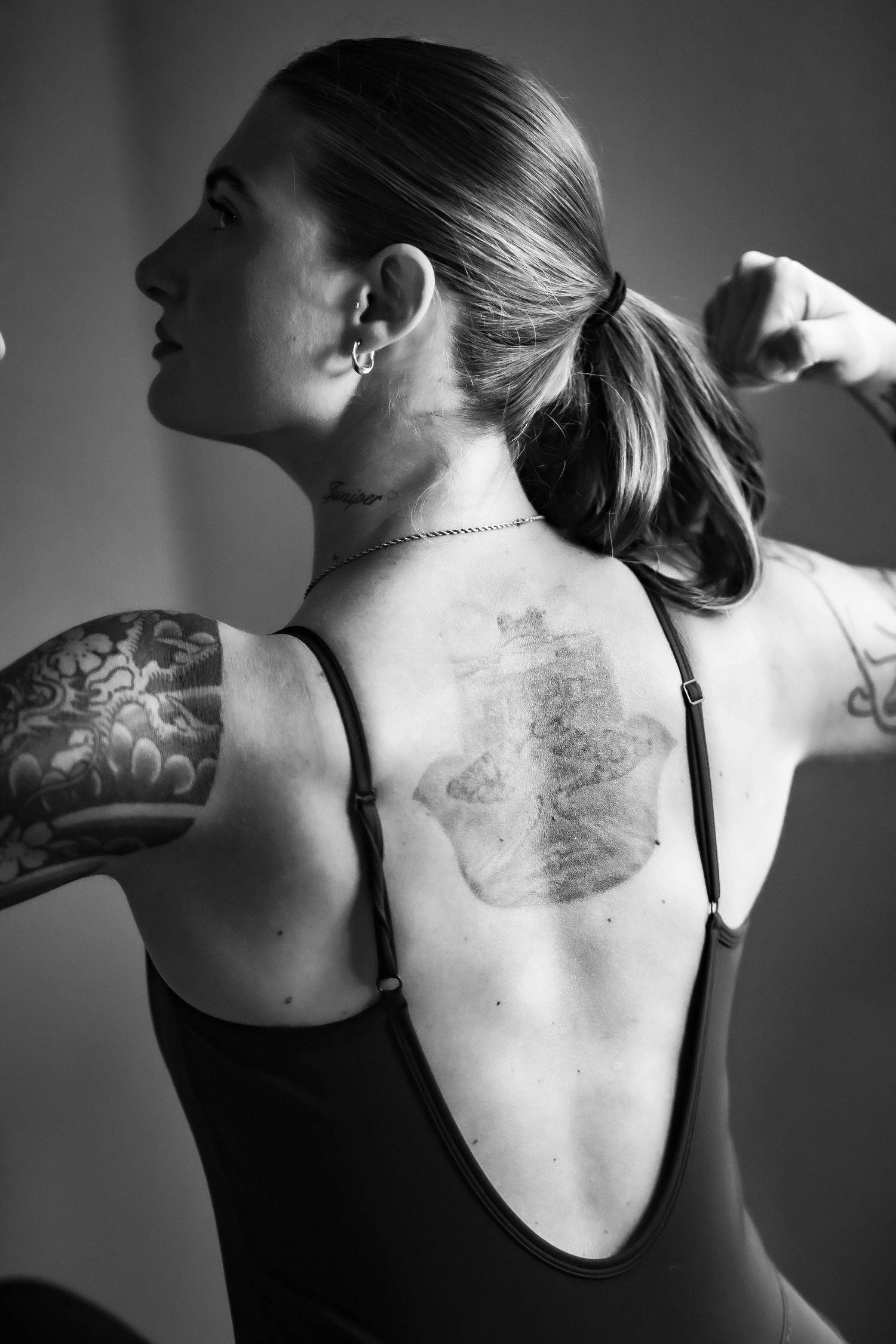 Black and white artistic photo series showing a back tattoo from multiple angles in dramatic lighting.