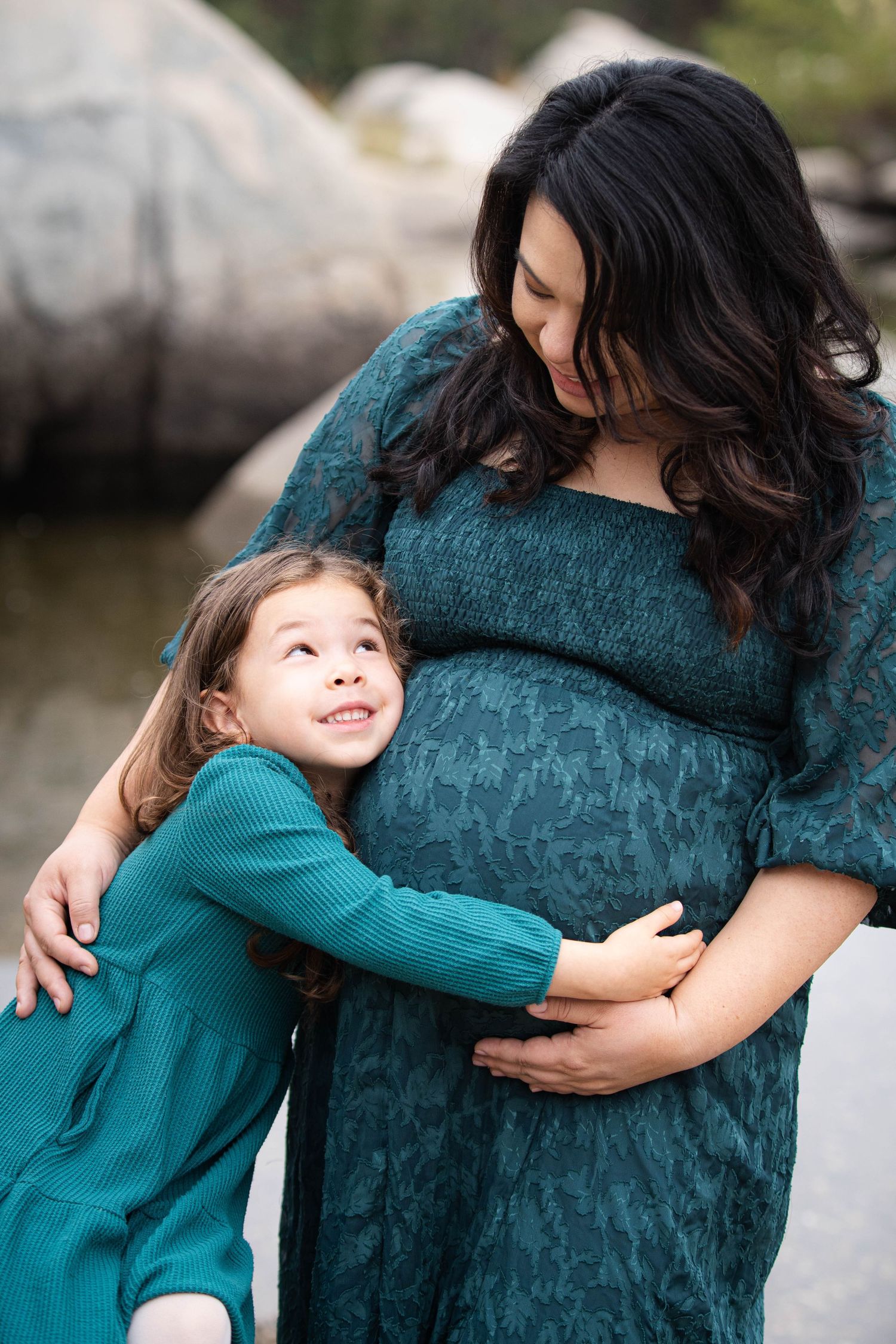 Sweet moments of a child hugging and bonding with family member wearing teal dress.