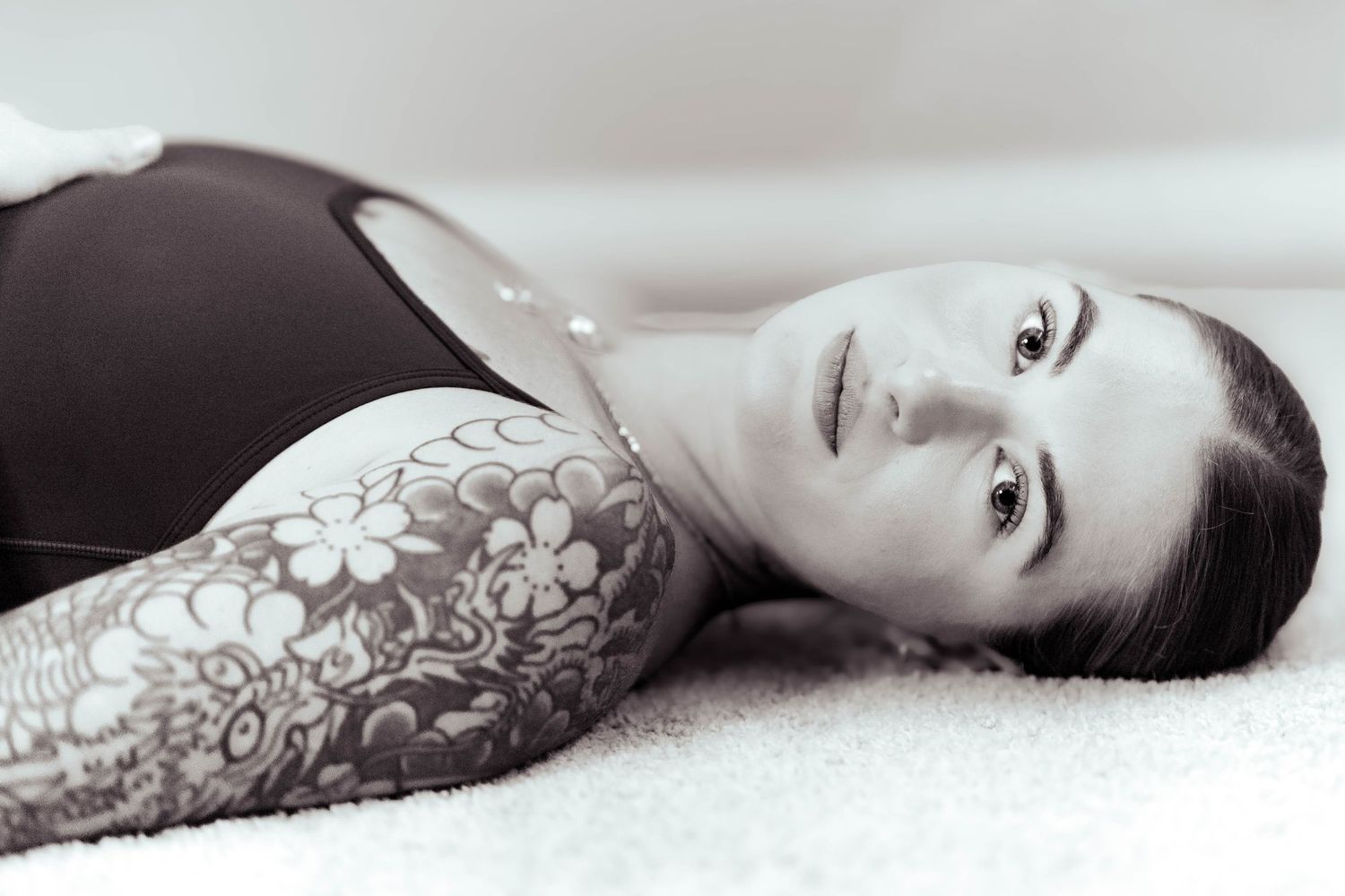 Minimalist black and white photography highlighting ornate floral tattoo artwork.