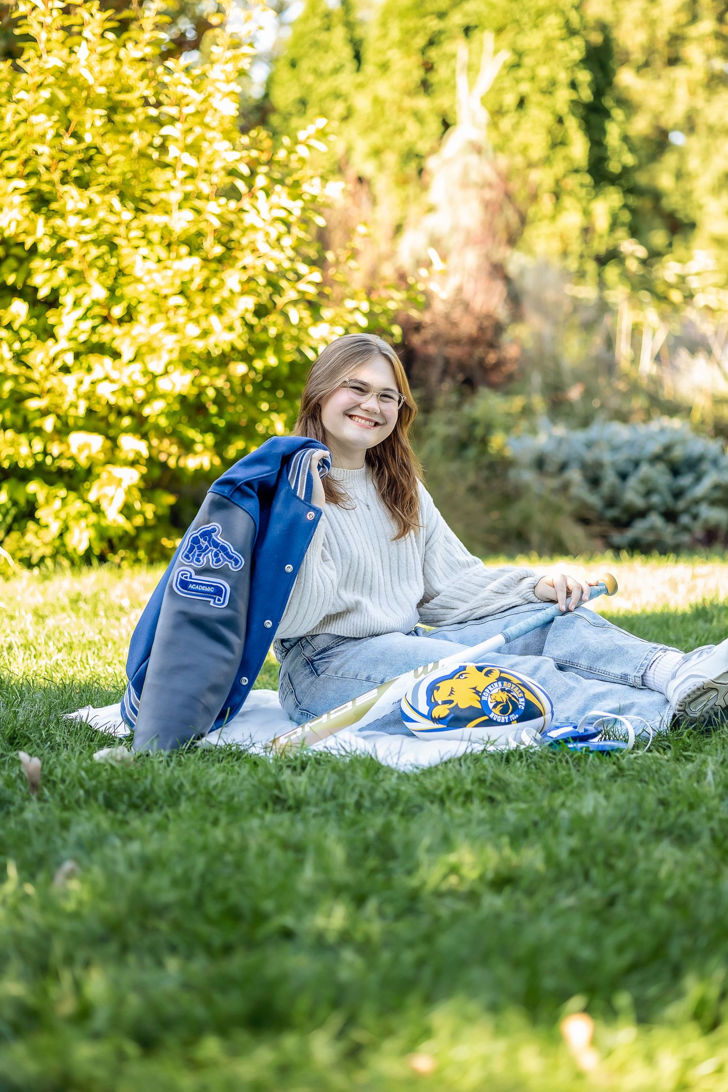 Girl in the grass with sports jacket and bat