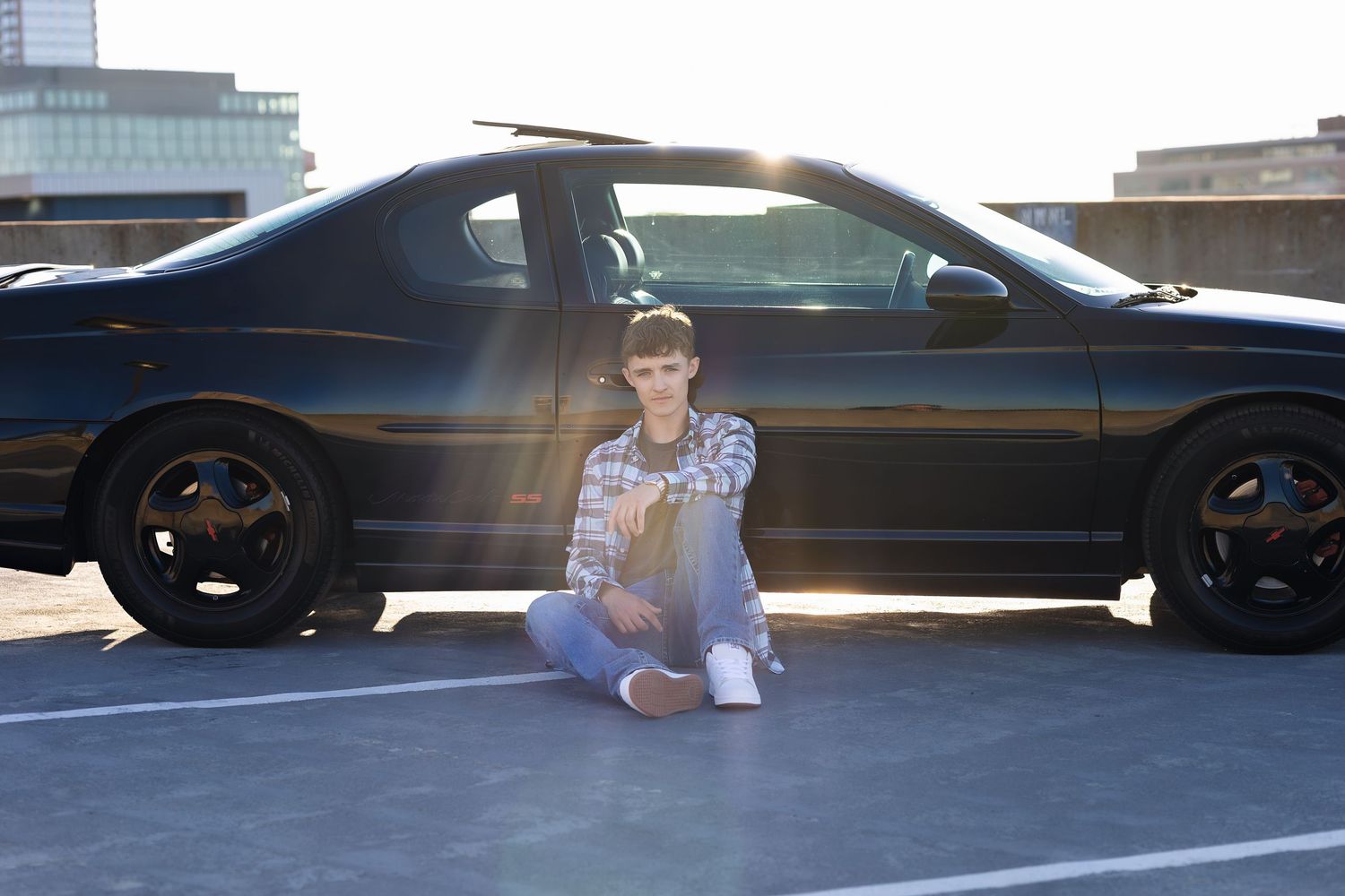 Young boy posing next to black car