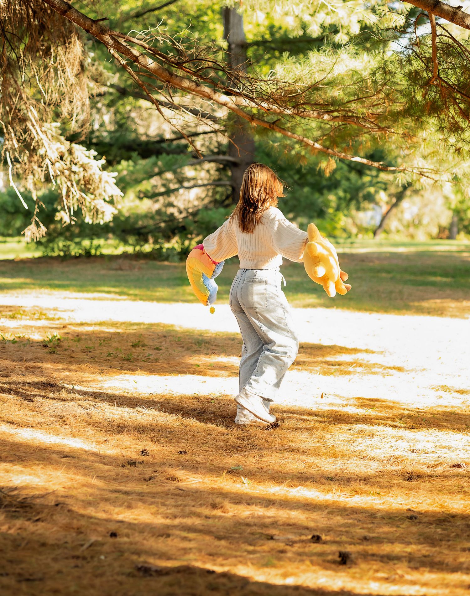 Young lady twirling in the pines with stuffed animals