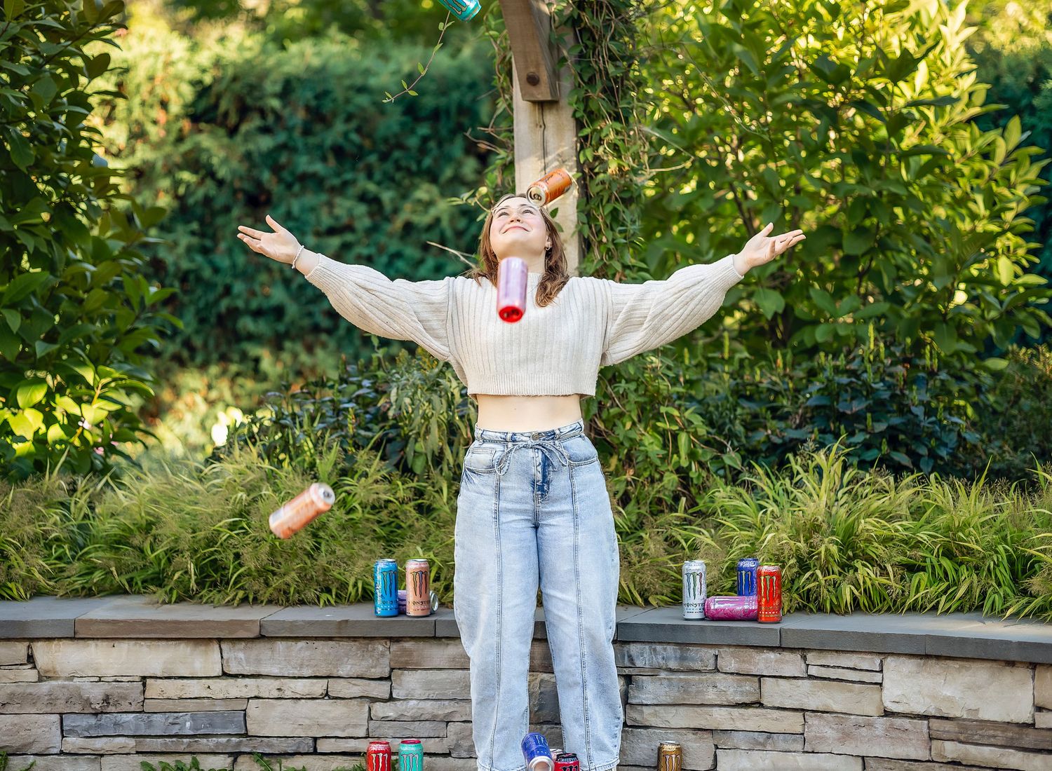 Girl throwing Monster Energy drink cans up into the air