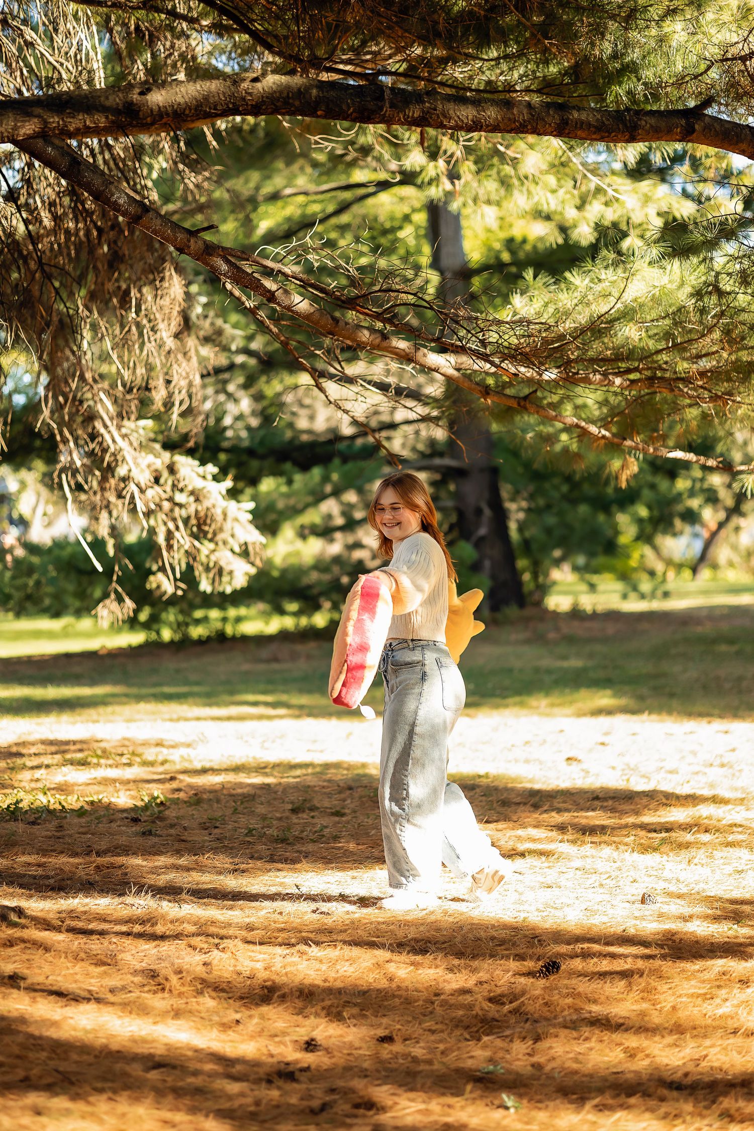 Young lady spinning in the woods with her stuffed animals