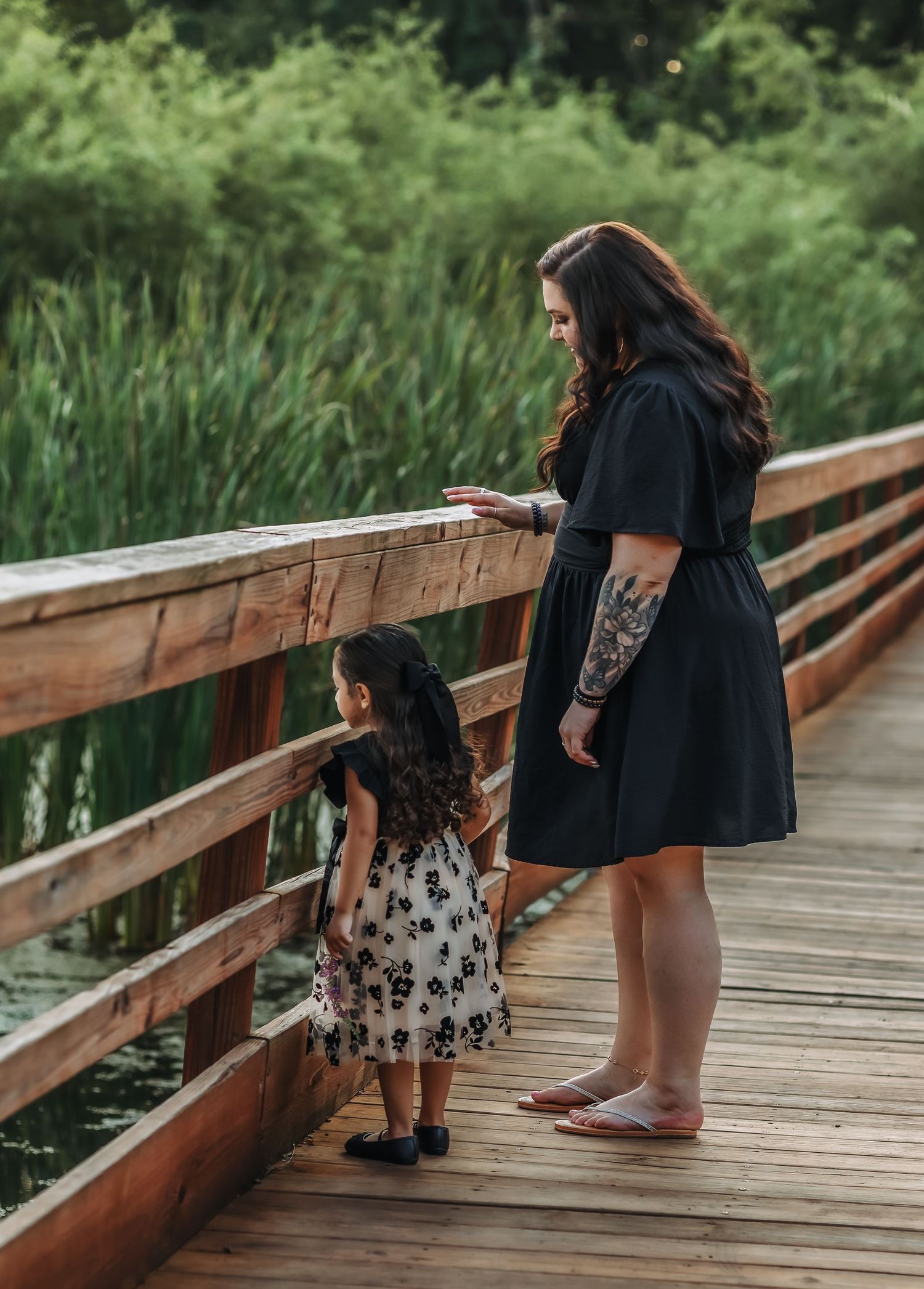 Mother and daughter looking out into the water from the side of the bridge.