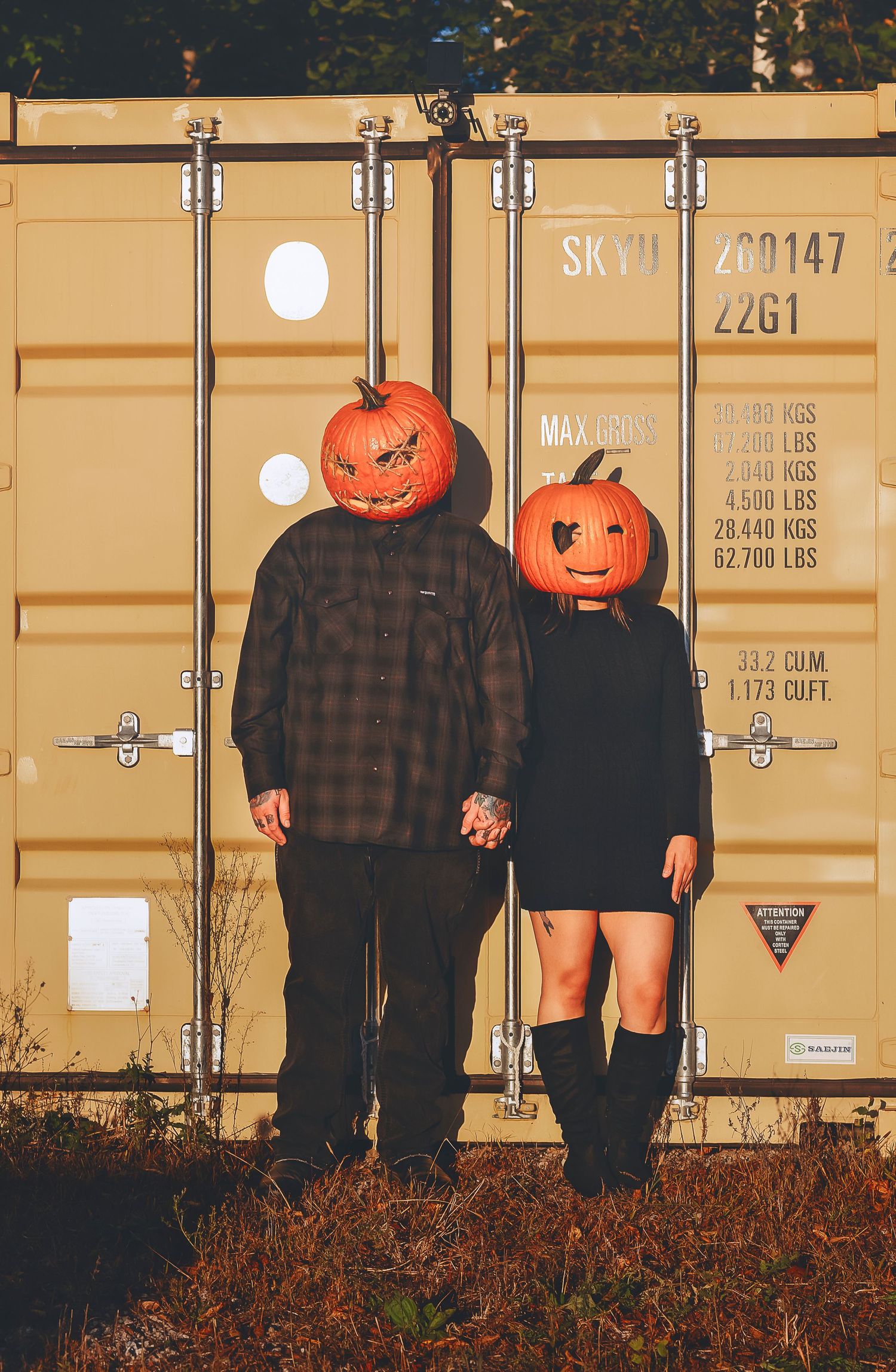 couple holding hands with pumpkin heads on