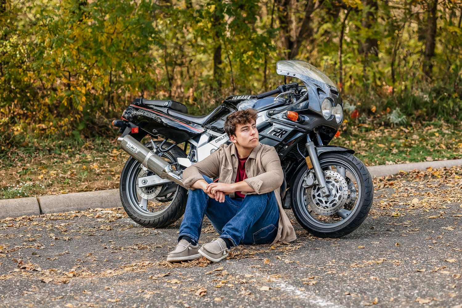 Boy sitting on the ground next to motorcycle