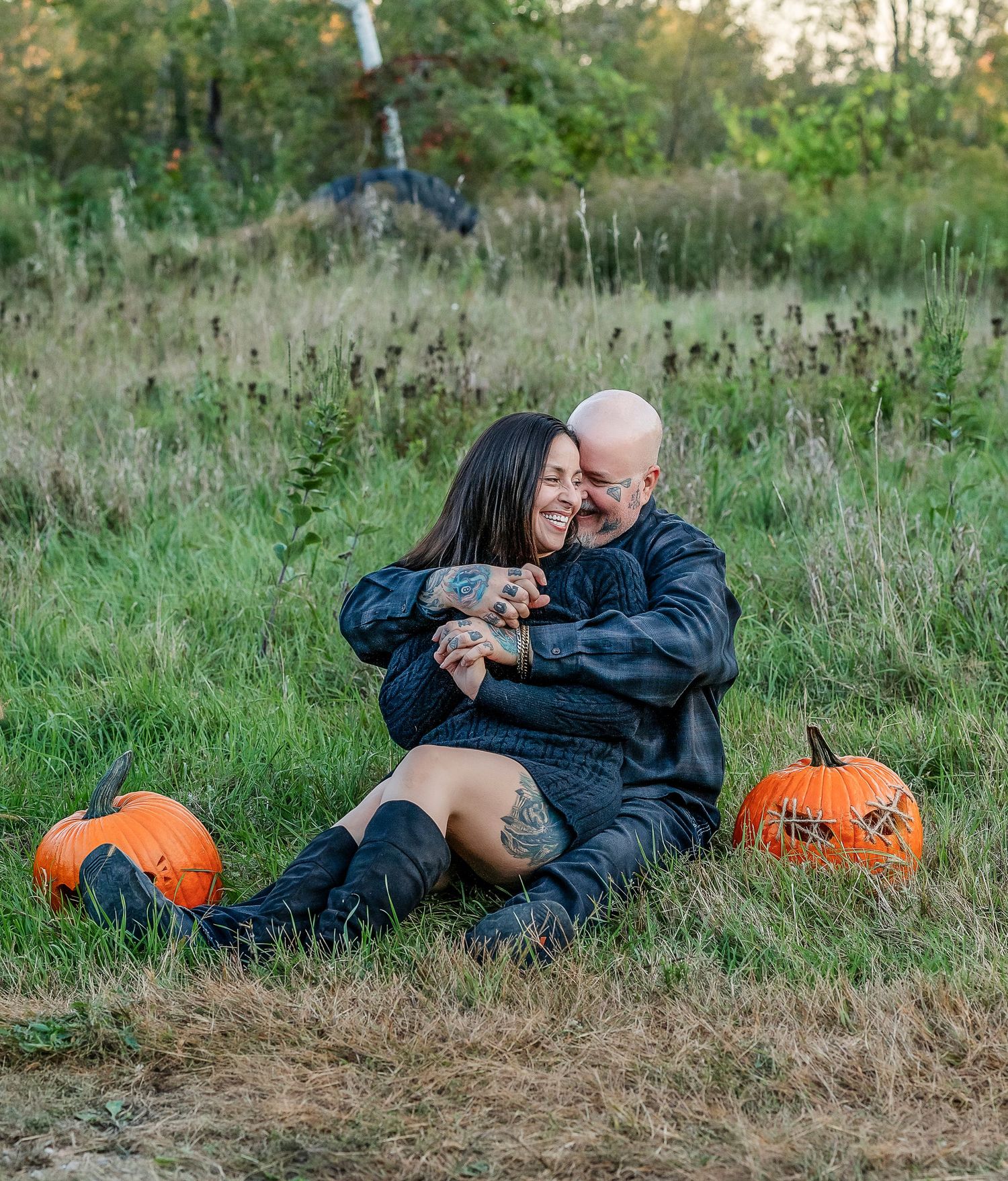 Man holding a woman in the grass with jack o lanterns
