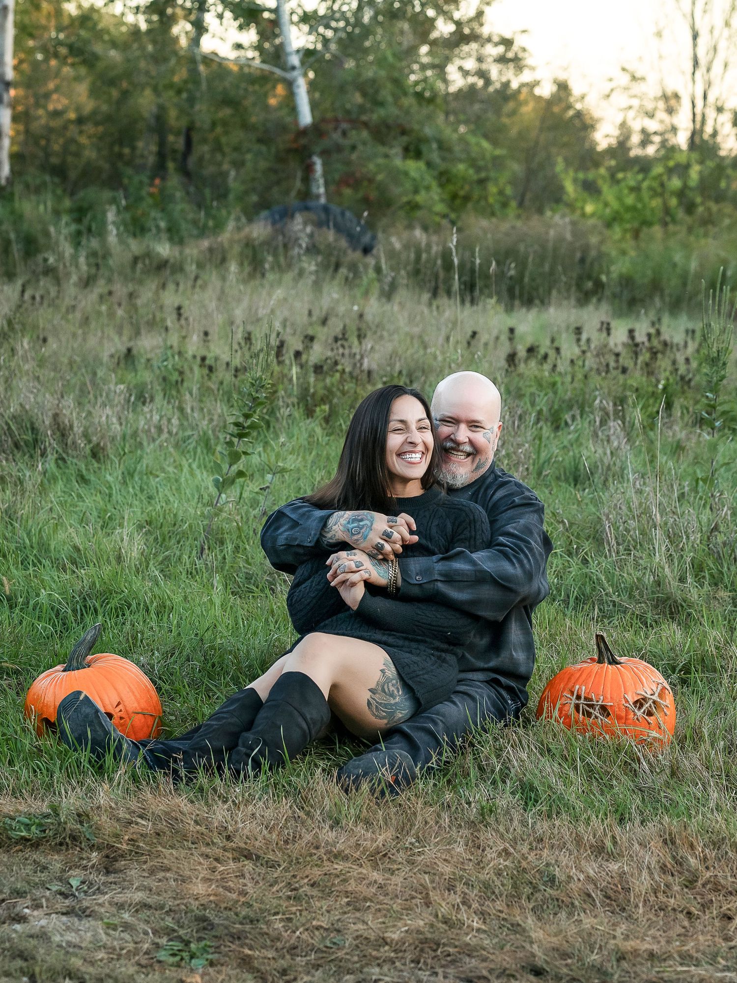 Couple smiling together in the grass at Halloween time