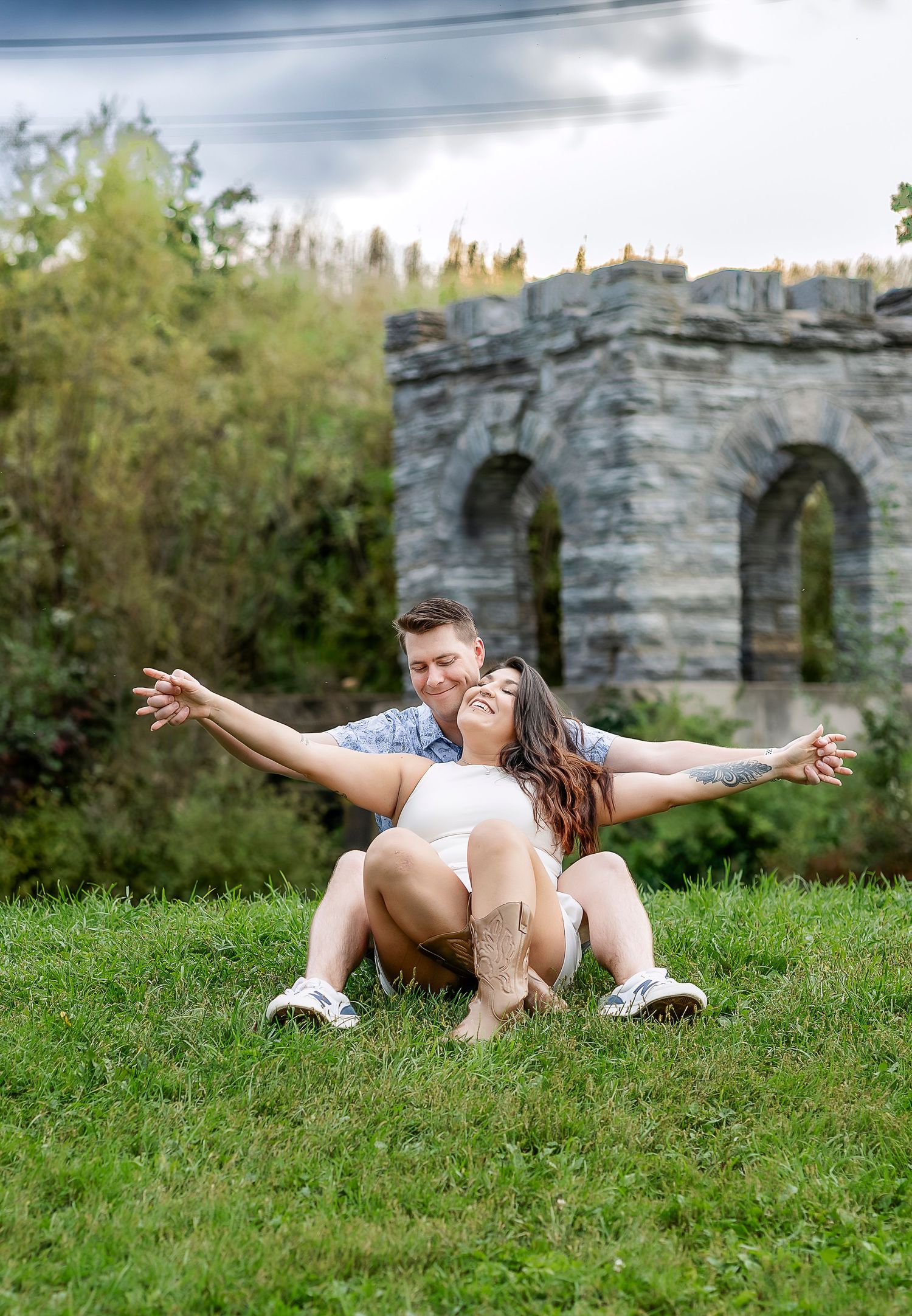 Man and woman holding arms out together sitting in the grass