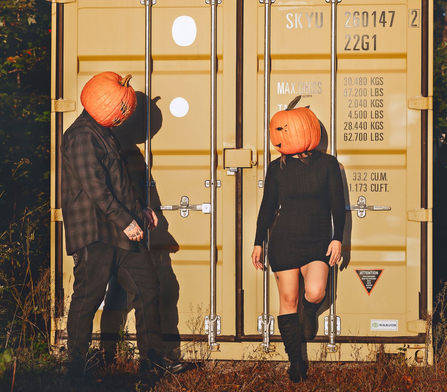 Man walking towards a woman, both are wearing pumpkin heads