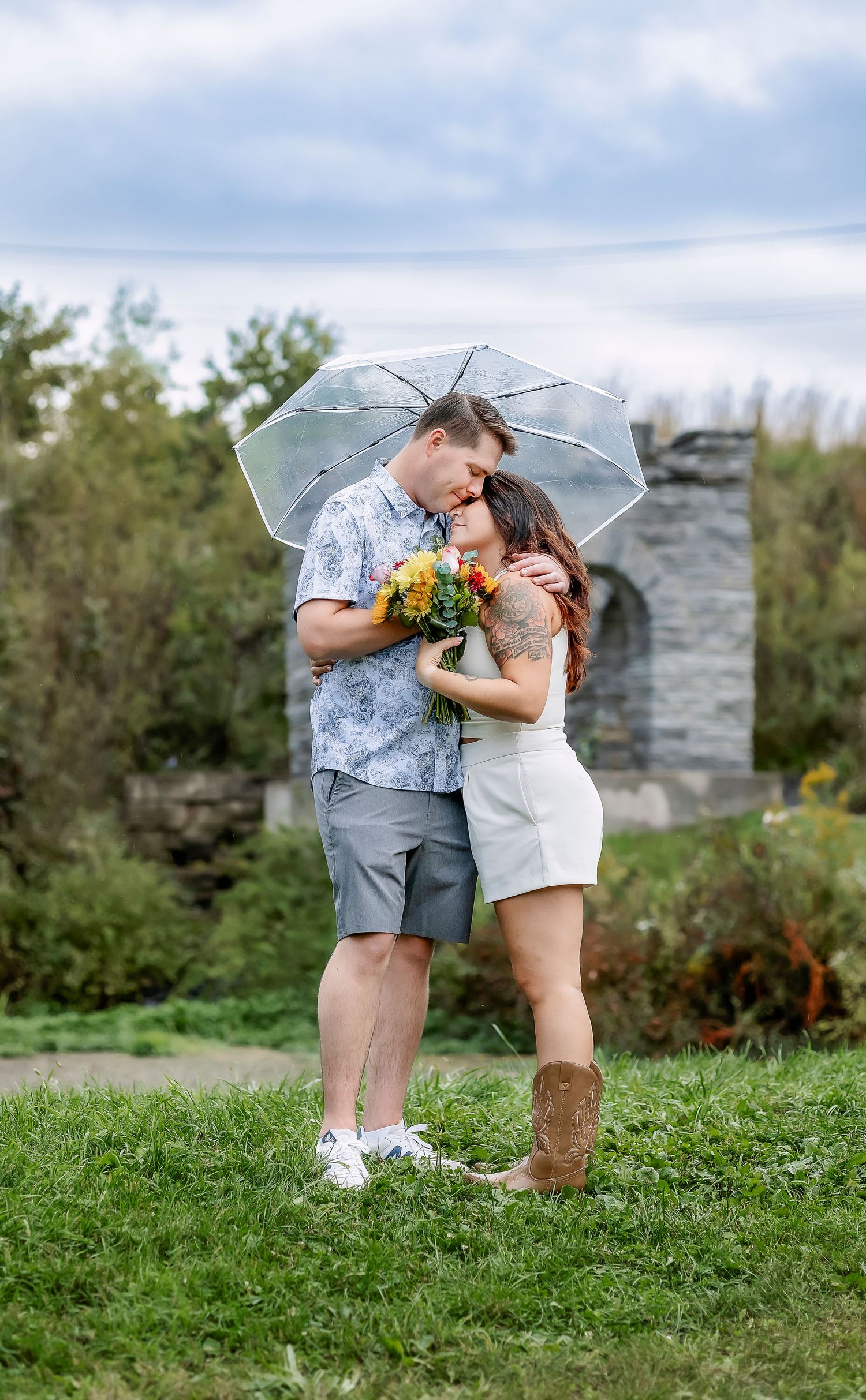 Couple snuggling together under clear umbrella