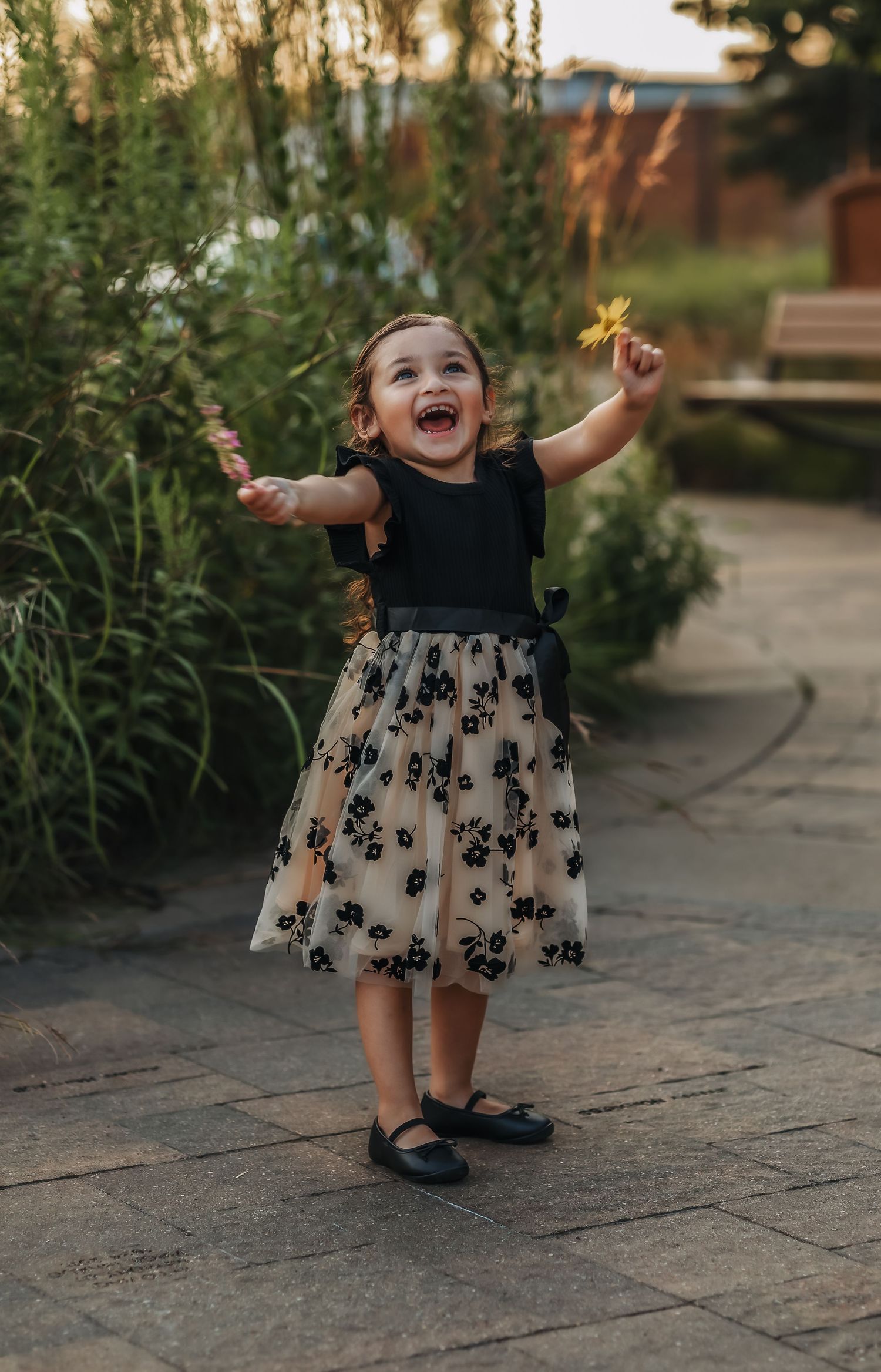 Small child holding flowers with arms up in the air
