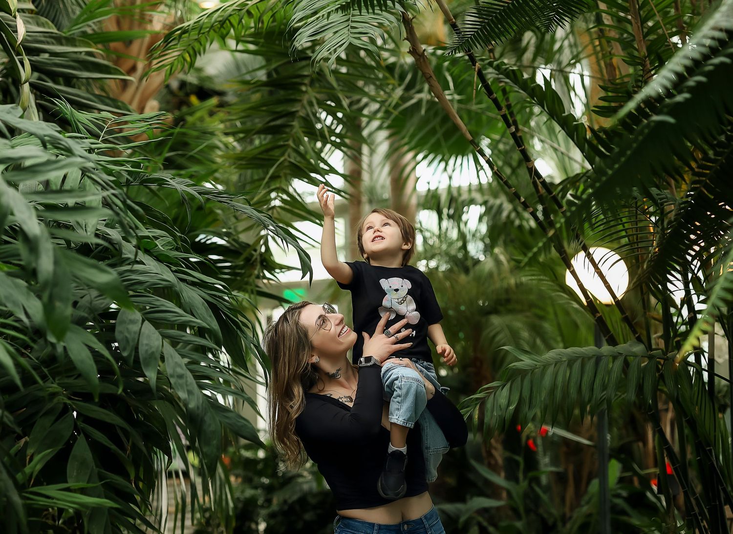 Mother and son in a garden, son is reaching for something up high
