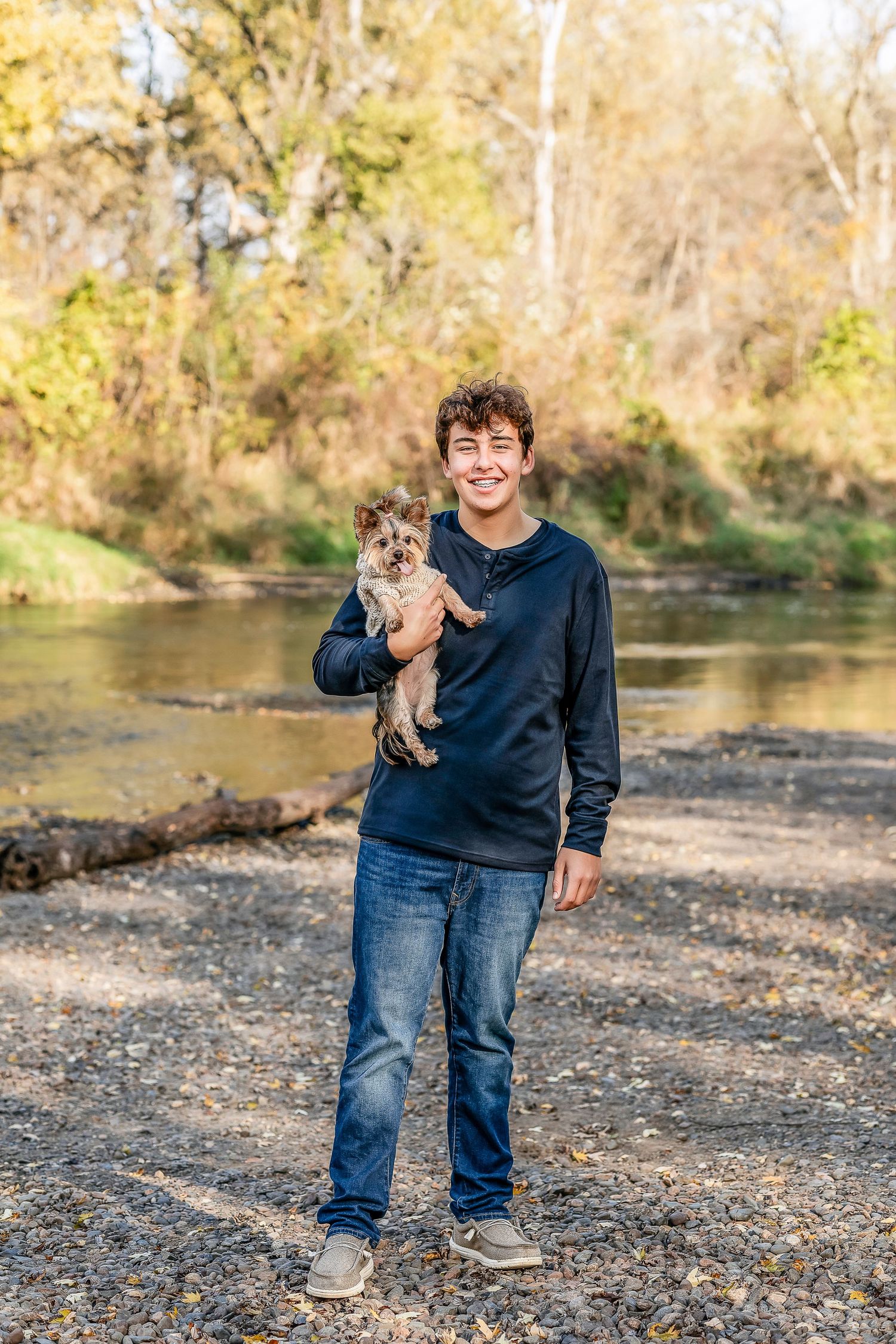 Young man wearing a black shirt and jeans holding a puppy and smiling