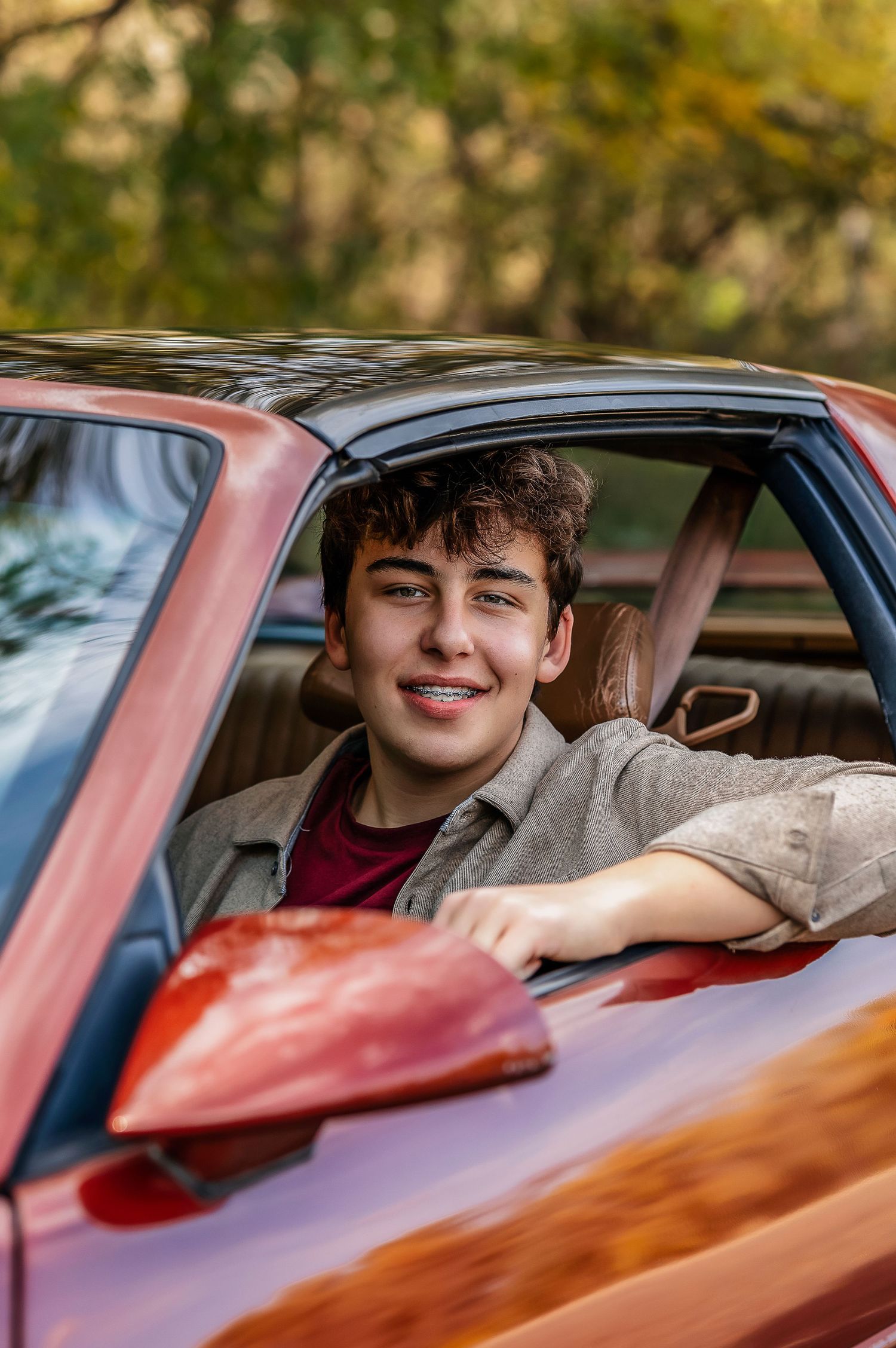 Young boy sitting in a red car smiling