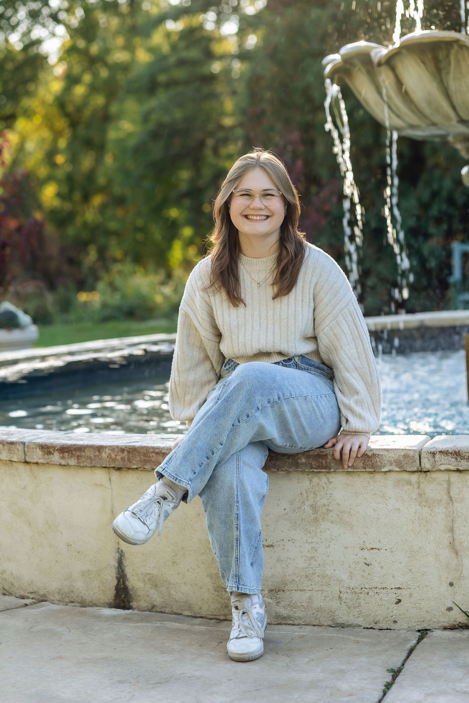 Girl sitting with legs crossed on the side of water fountain