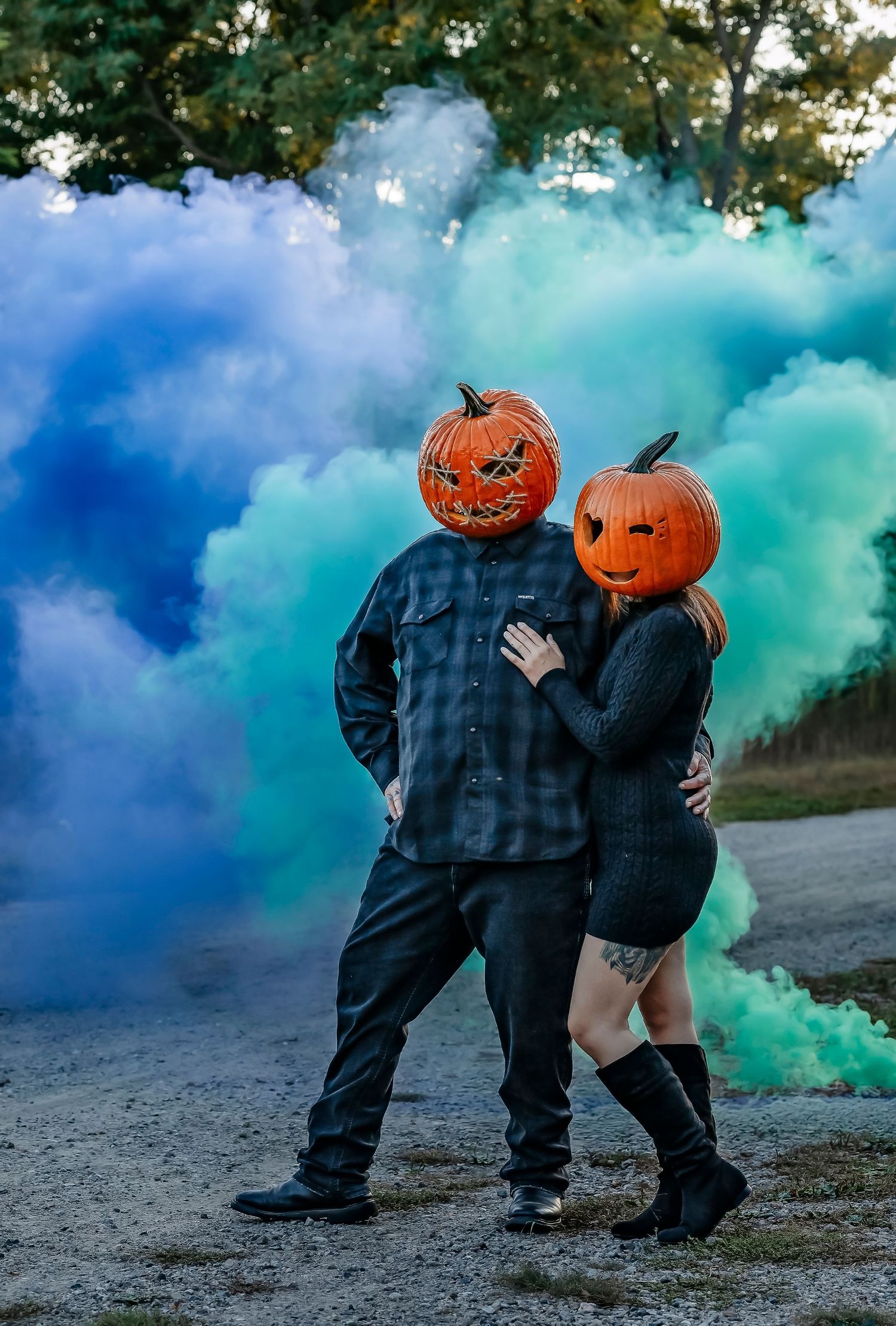 Pumpkin head couple posing in front of green and blue smoke bomb