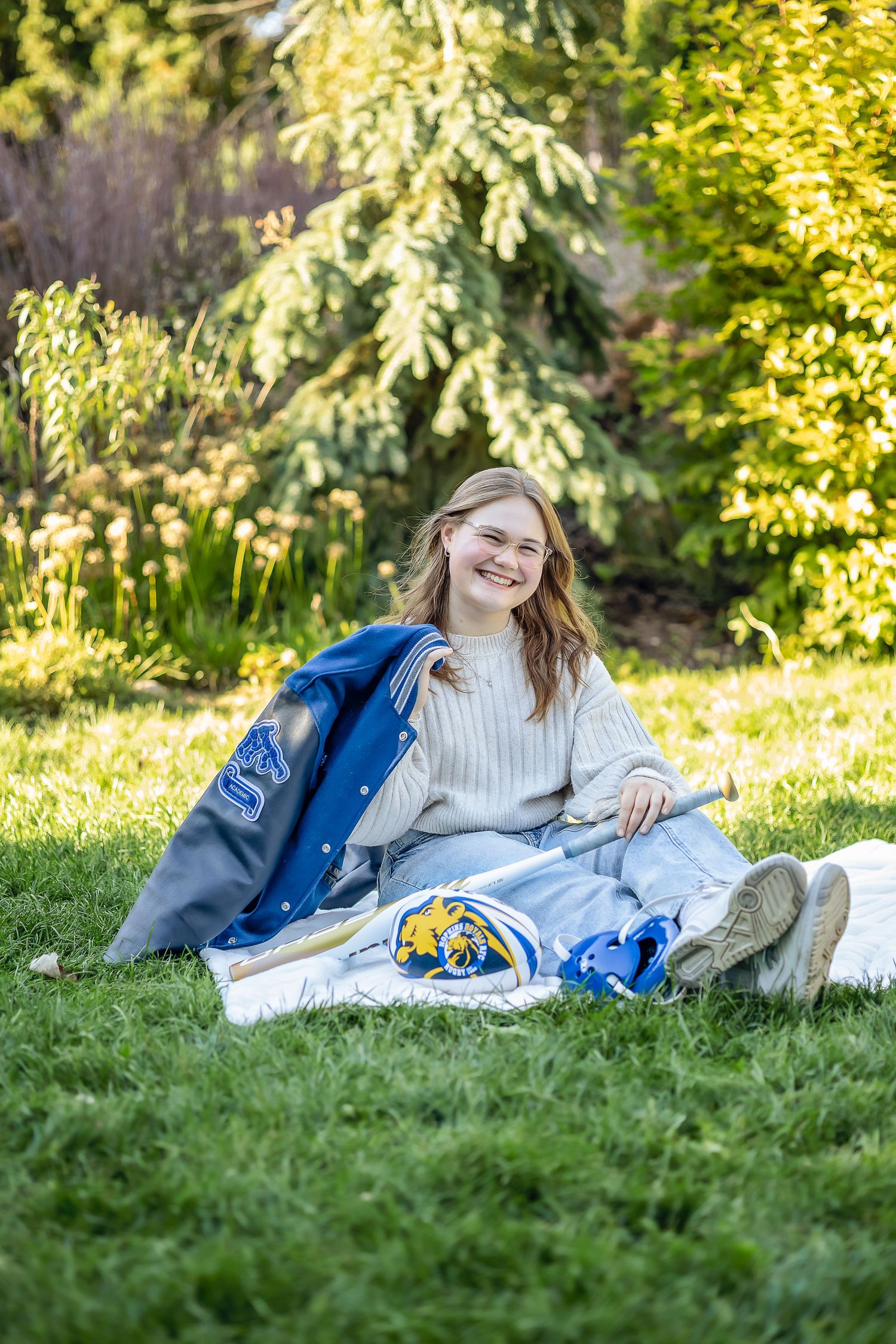 Girl sitting in the grass with sports things